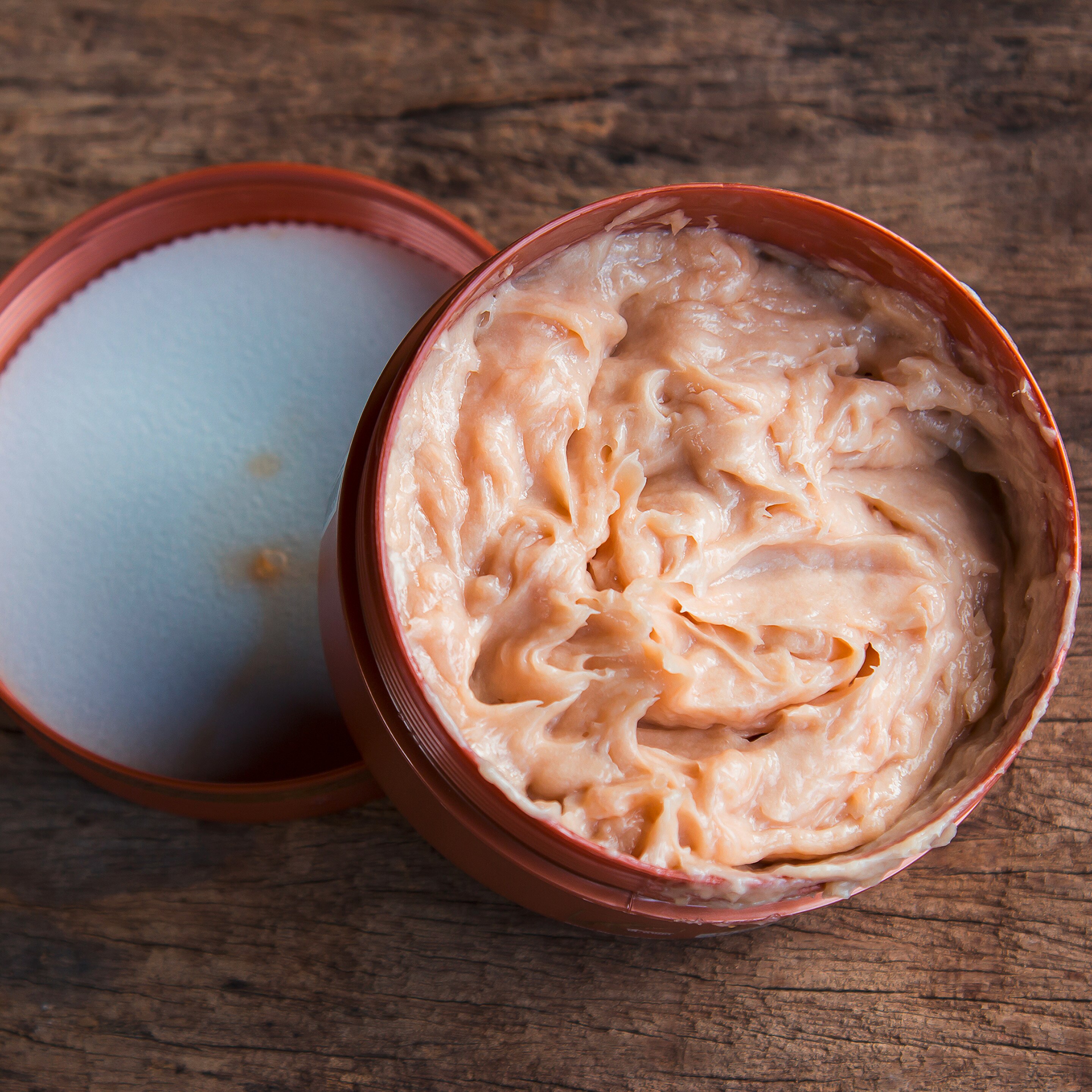 Expired brown lotion in plastic tub.