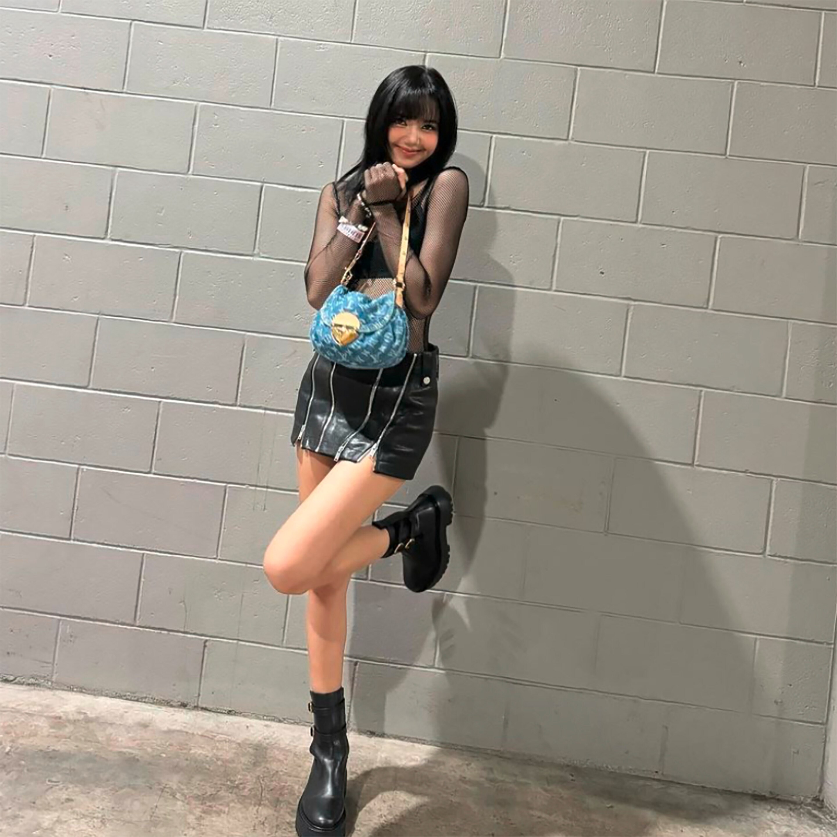 Lisa of Blackpink wearing black top, shirt, and boots.