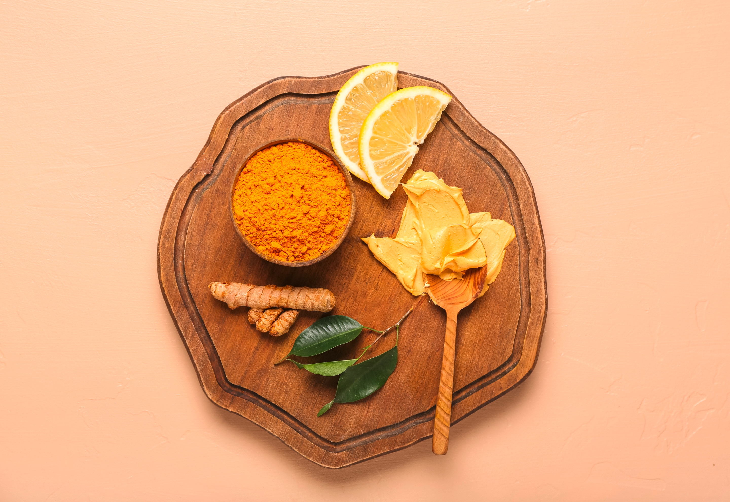 ผงขมิ้น ขมิ้น เลมอนฝาน เนื้อครีมสีเหลืองบนช้อนไม้ ใบไม้ วางบนถาดไม้