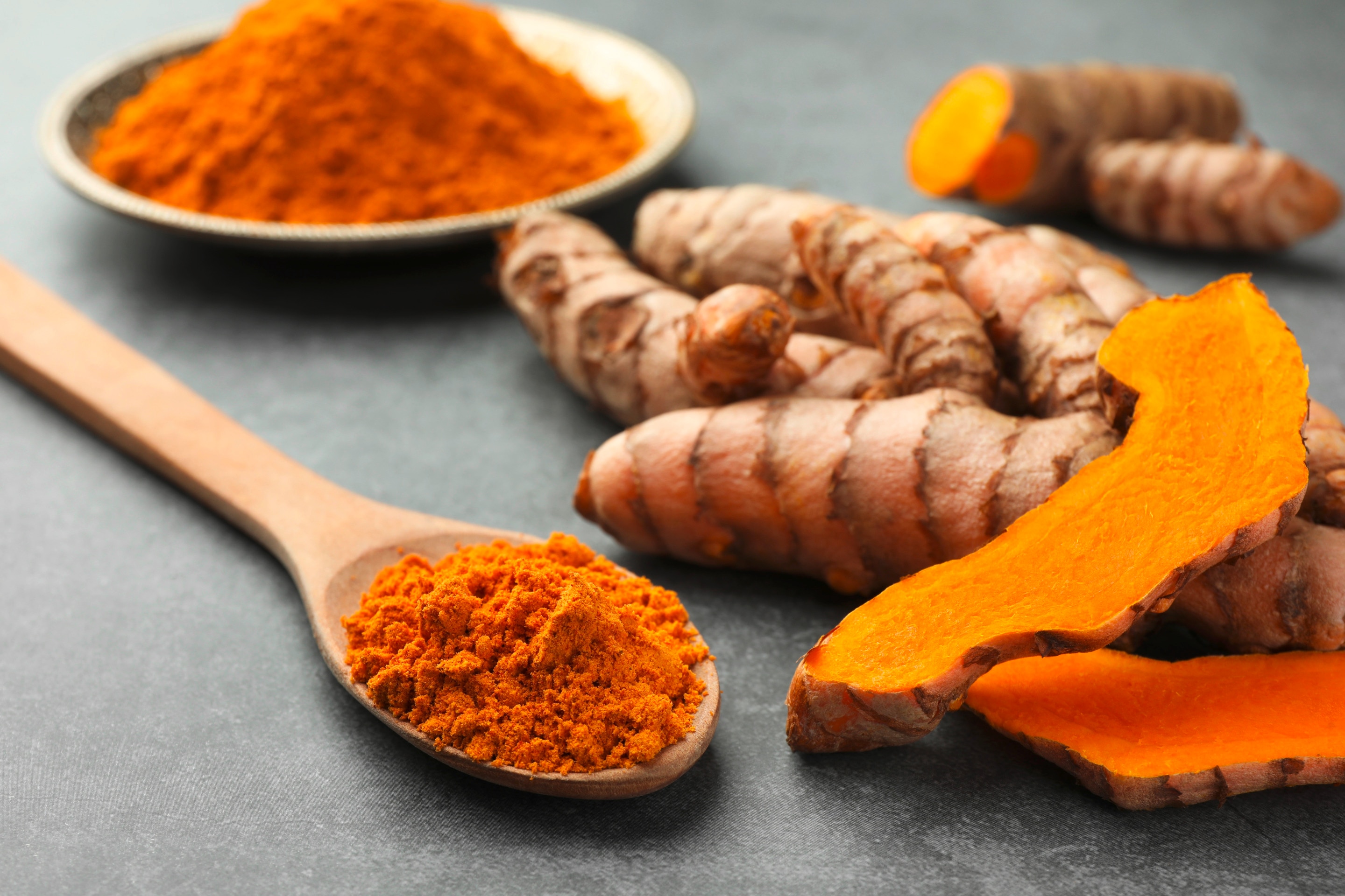 ผงขมิ้นในช้อนไม้ ถ้วยใส่ผงขมิ้น ขมิ้นชัน ขมิ้นผ่าครึ่ง