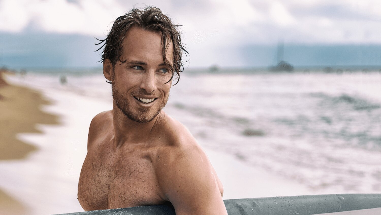  Young surfer with wet sweaty hair carrying his surfboard 