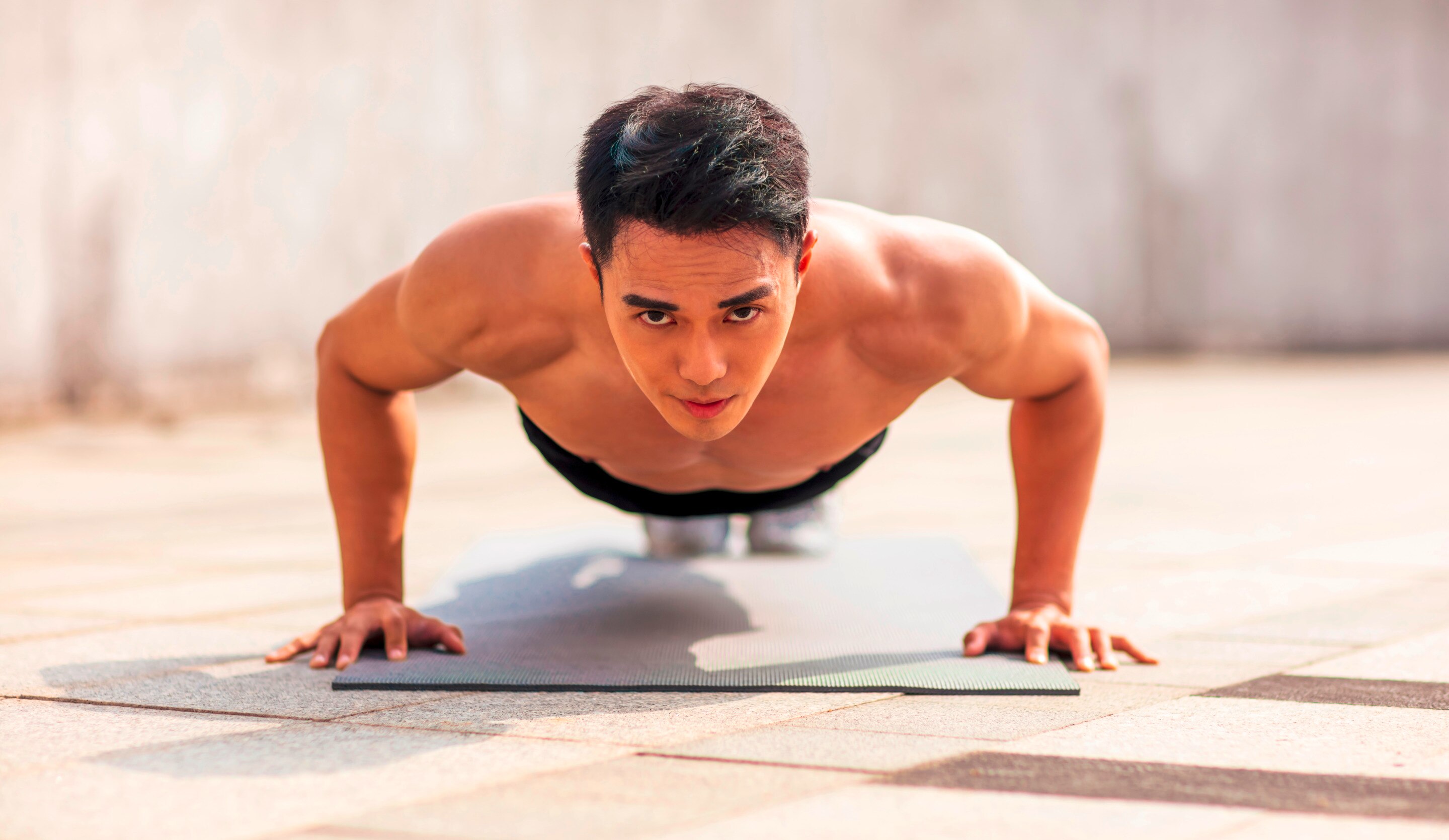 Man with a serious expression doing push-ups on the gym floor.
