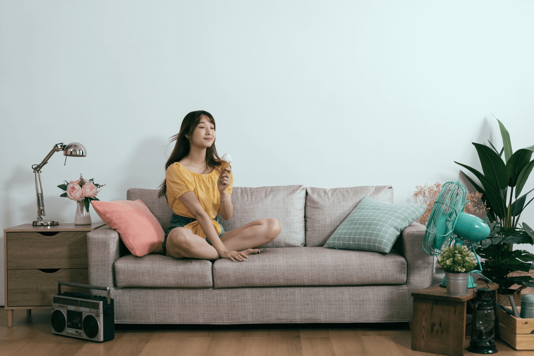 A young woman in her home enjoying a cool summer day indoors with her portable fans. 