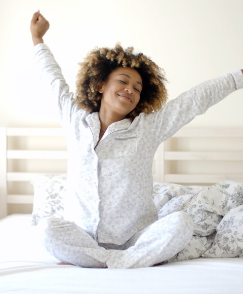 Young woman waking up happy with no sign of sweating during her night’s rest