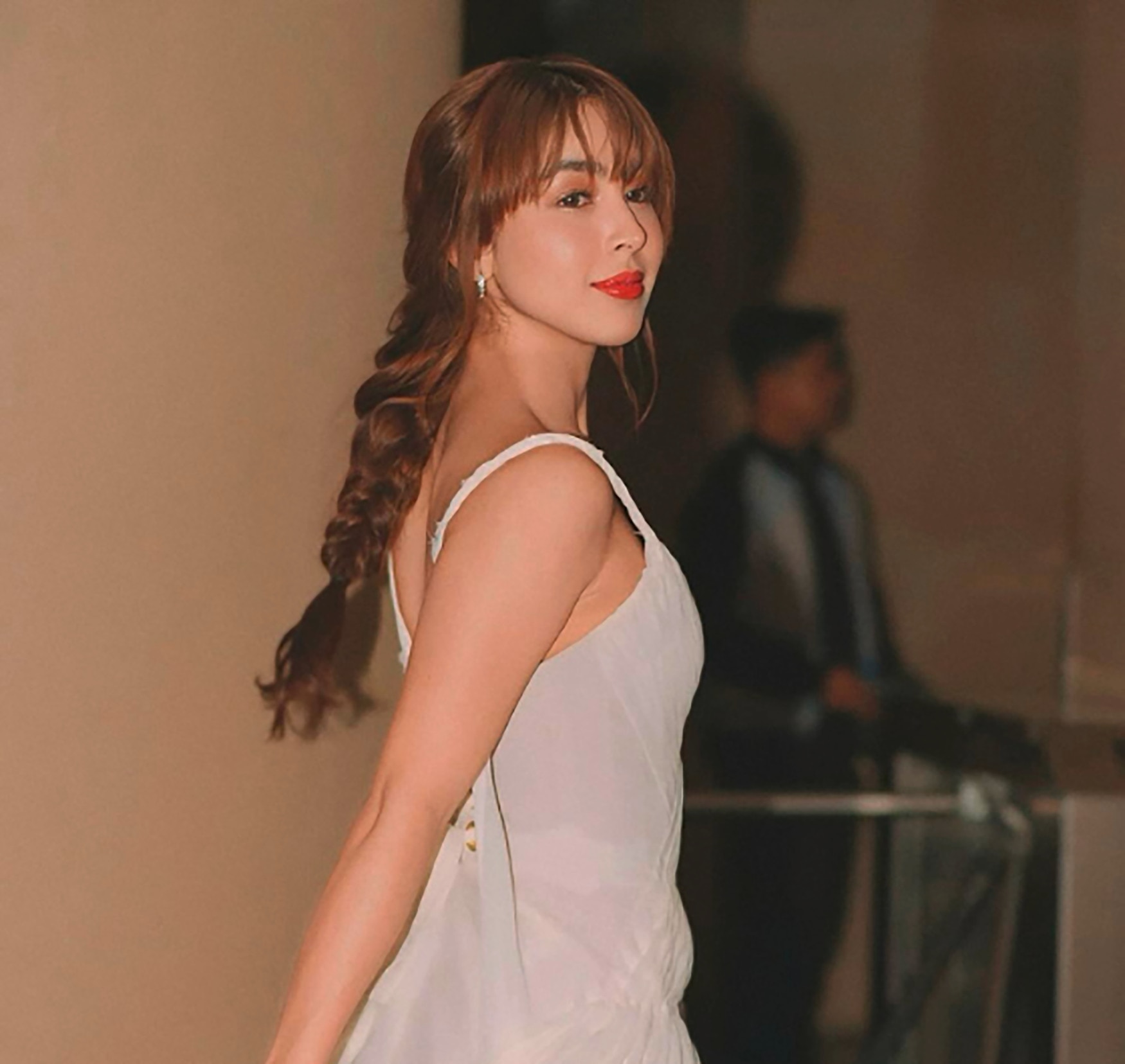 A Filipina actress looking back with a smile.