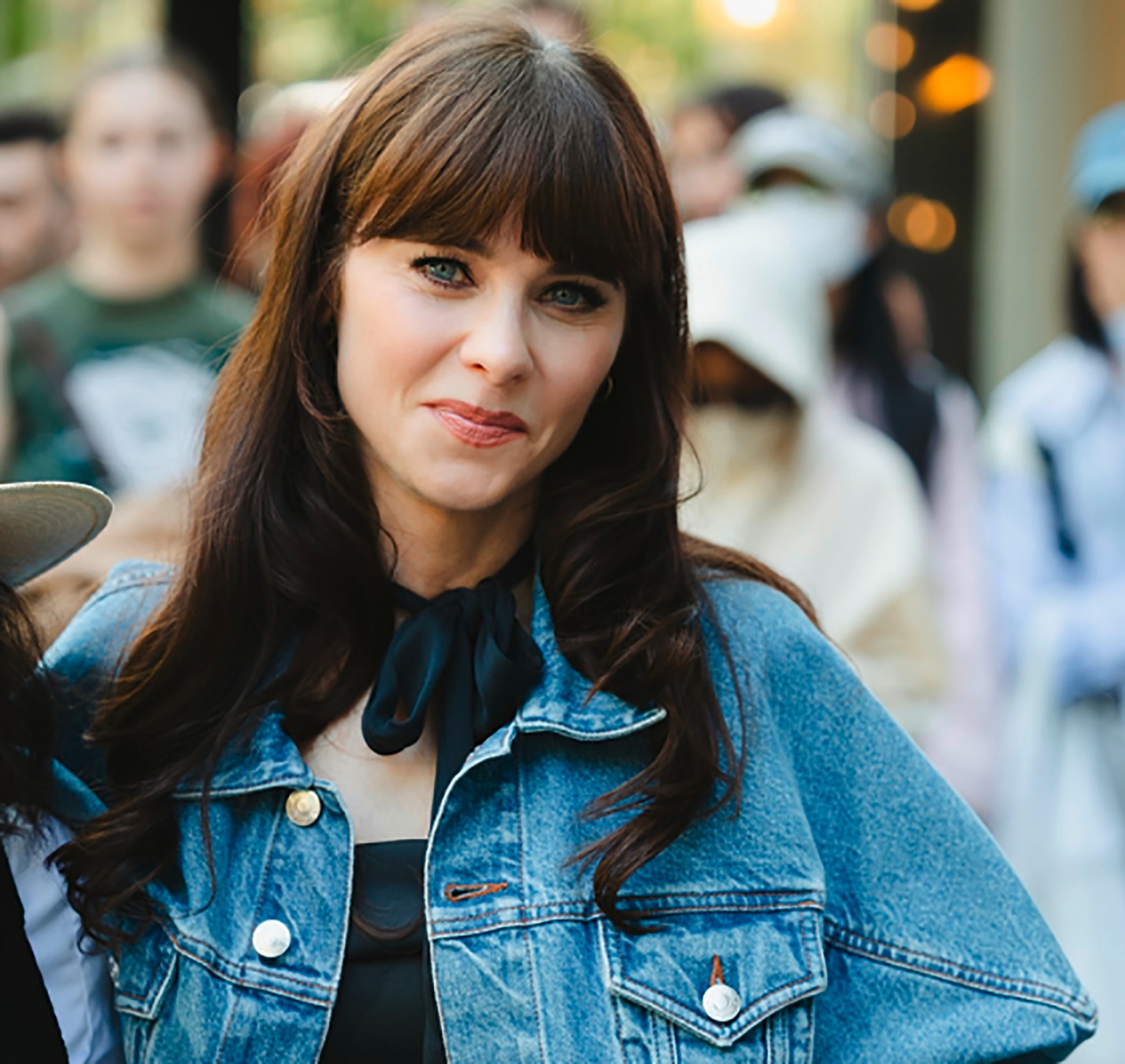 Woman in a dress and denim jacket outdoors.