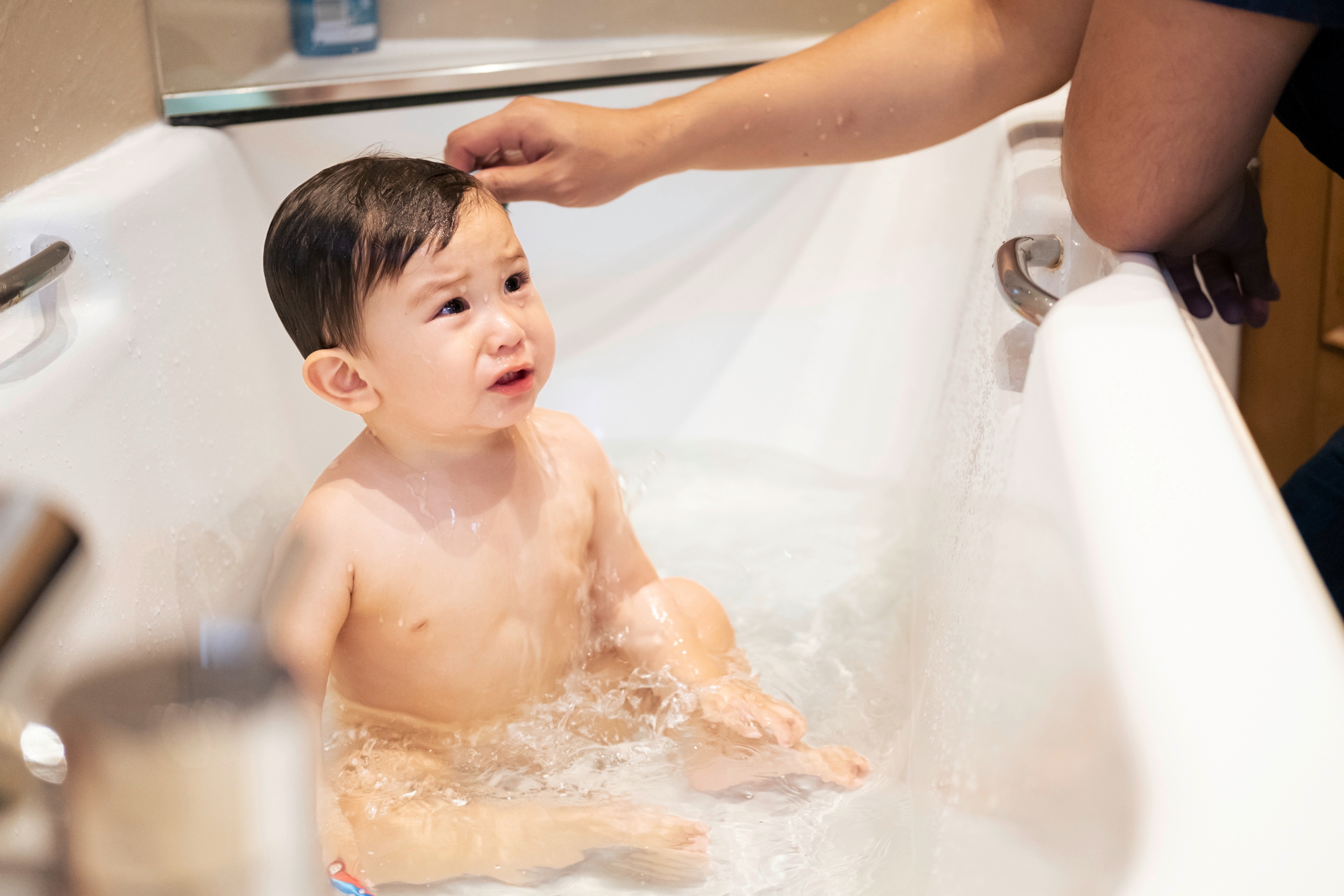 bayi yang sedang duduk di dalam bak mandi, terlihat menangis karena alergi sabun mandi