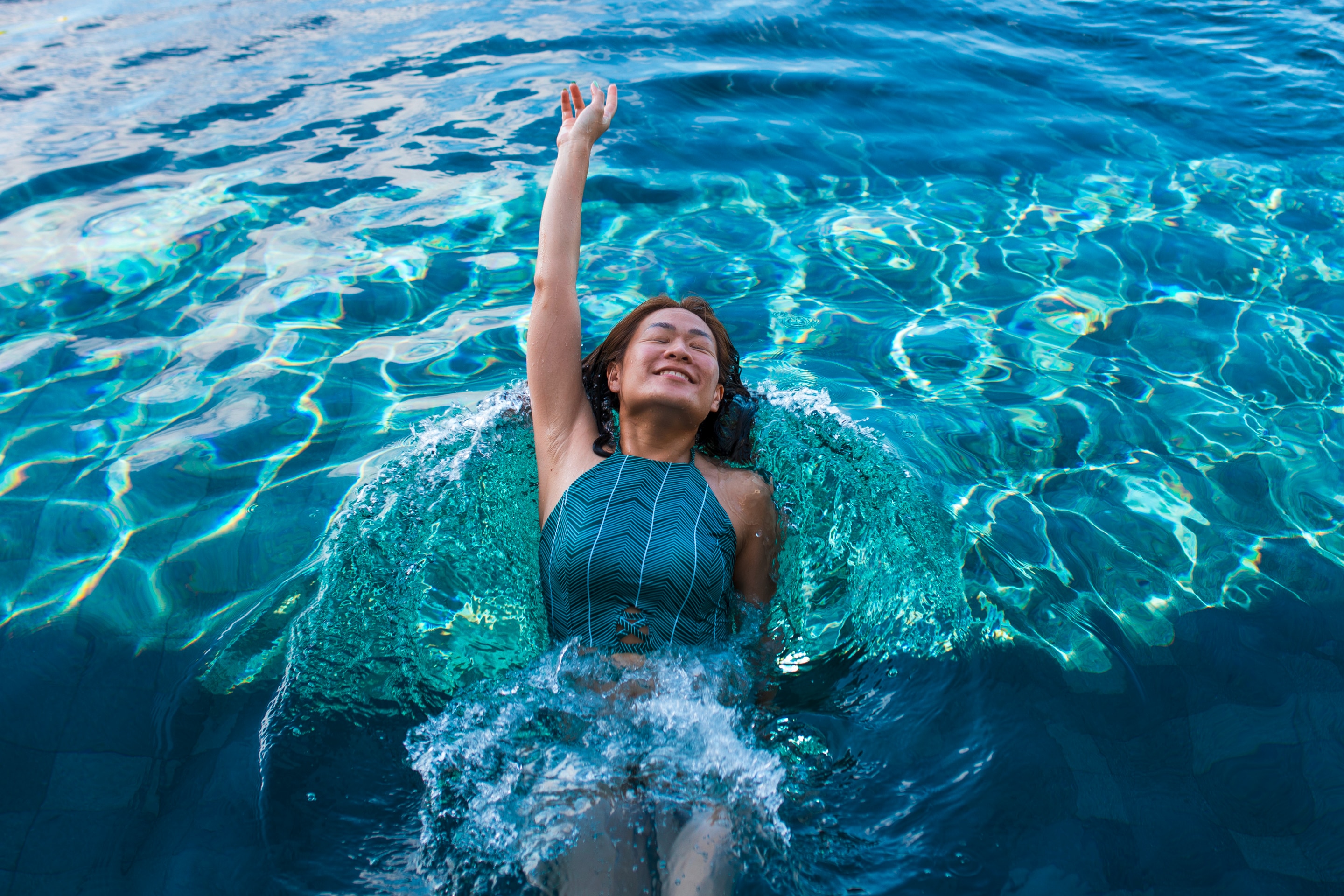 Asian woman swimming backstroke in swimming pool.