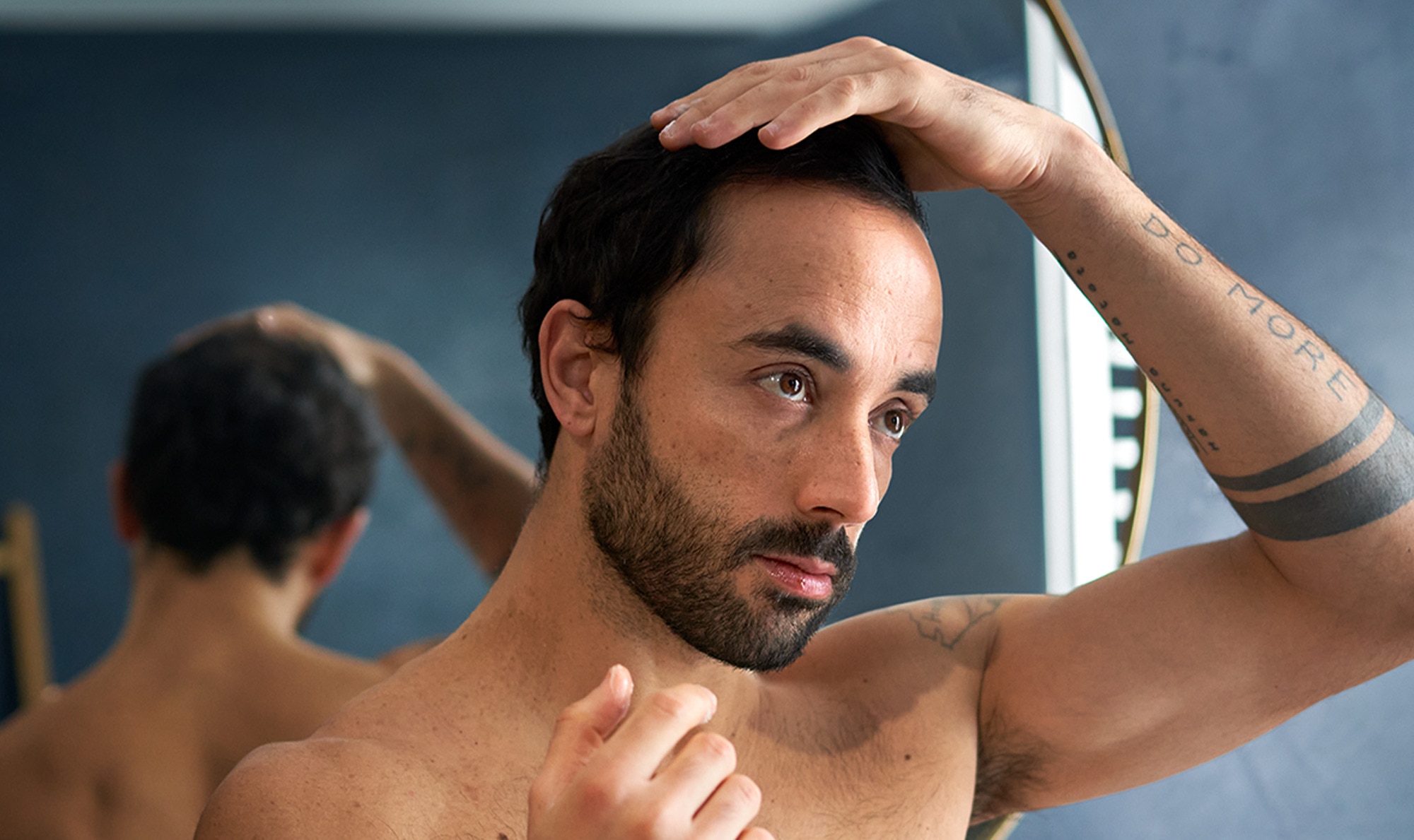 Man holding his head as he looks into the mirror