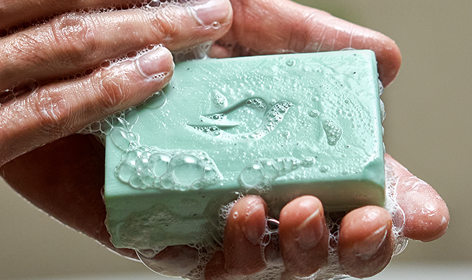 Hands lathering up Dove Men+Care bar