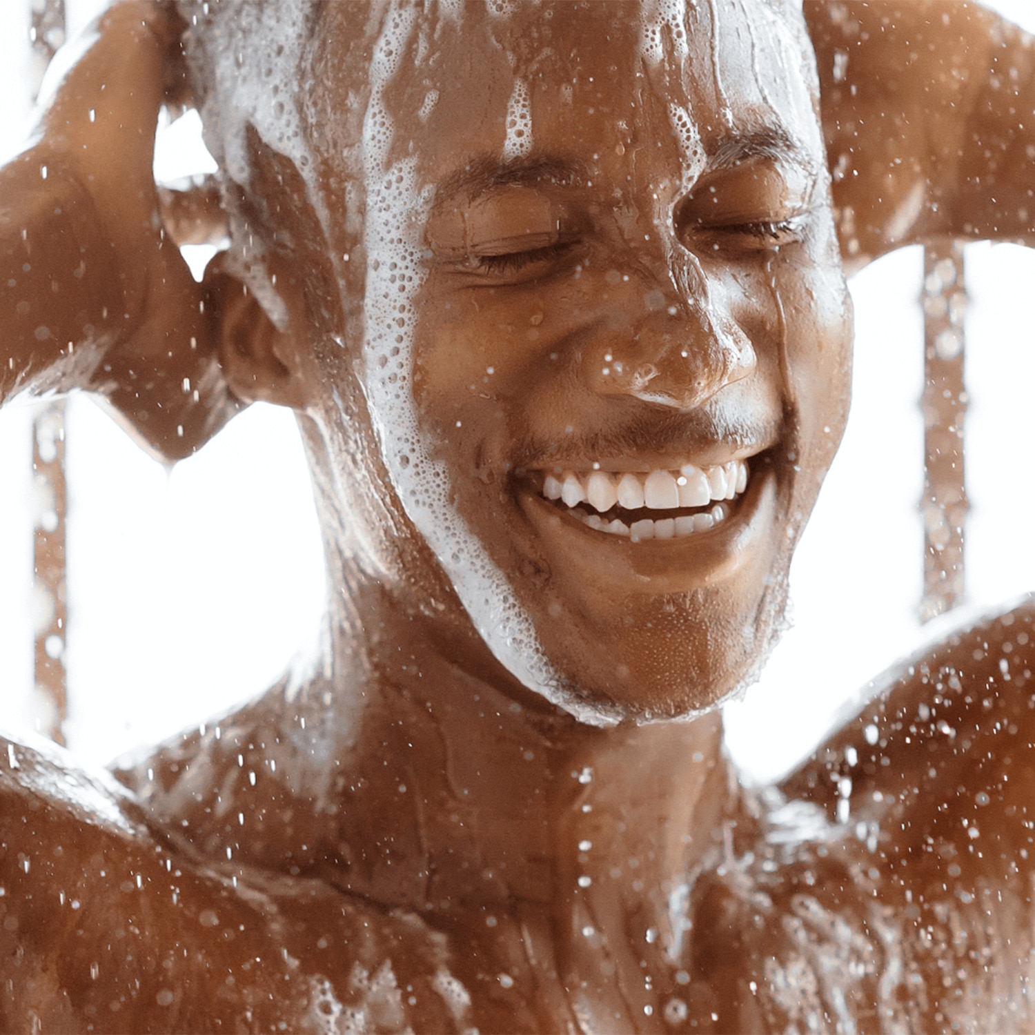 Man smiling while rinsing his face in the shower