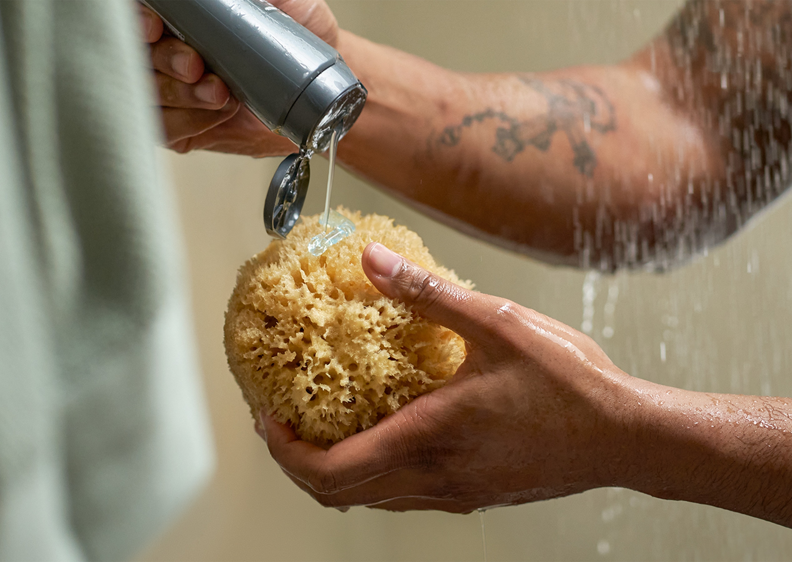 Hand squeezing body wash into a shower sponge.