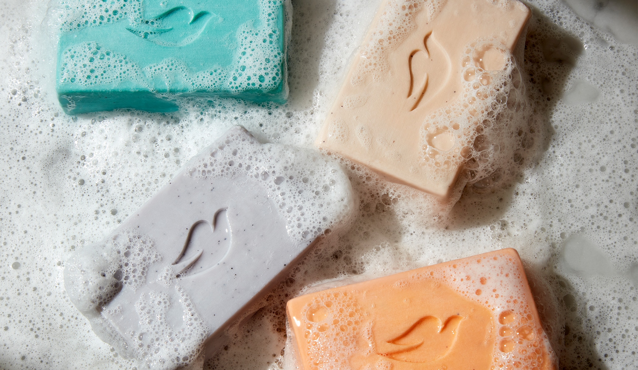 Four colorful lathered Dove Men+Care cleansing bars 