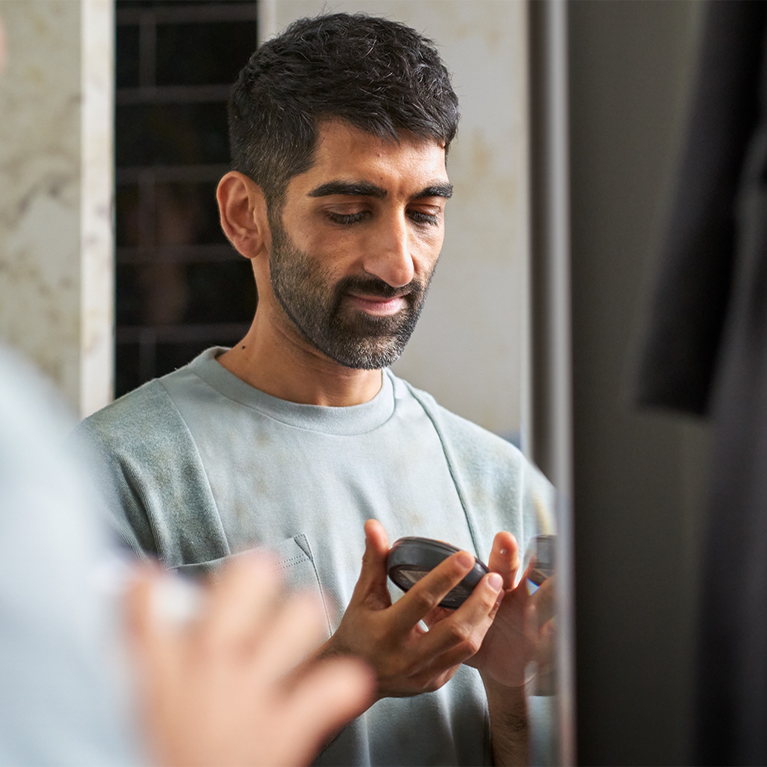 Smiling man looking down opening a cream jar