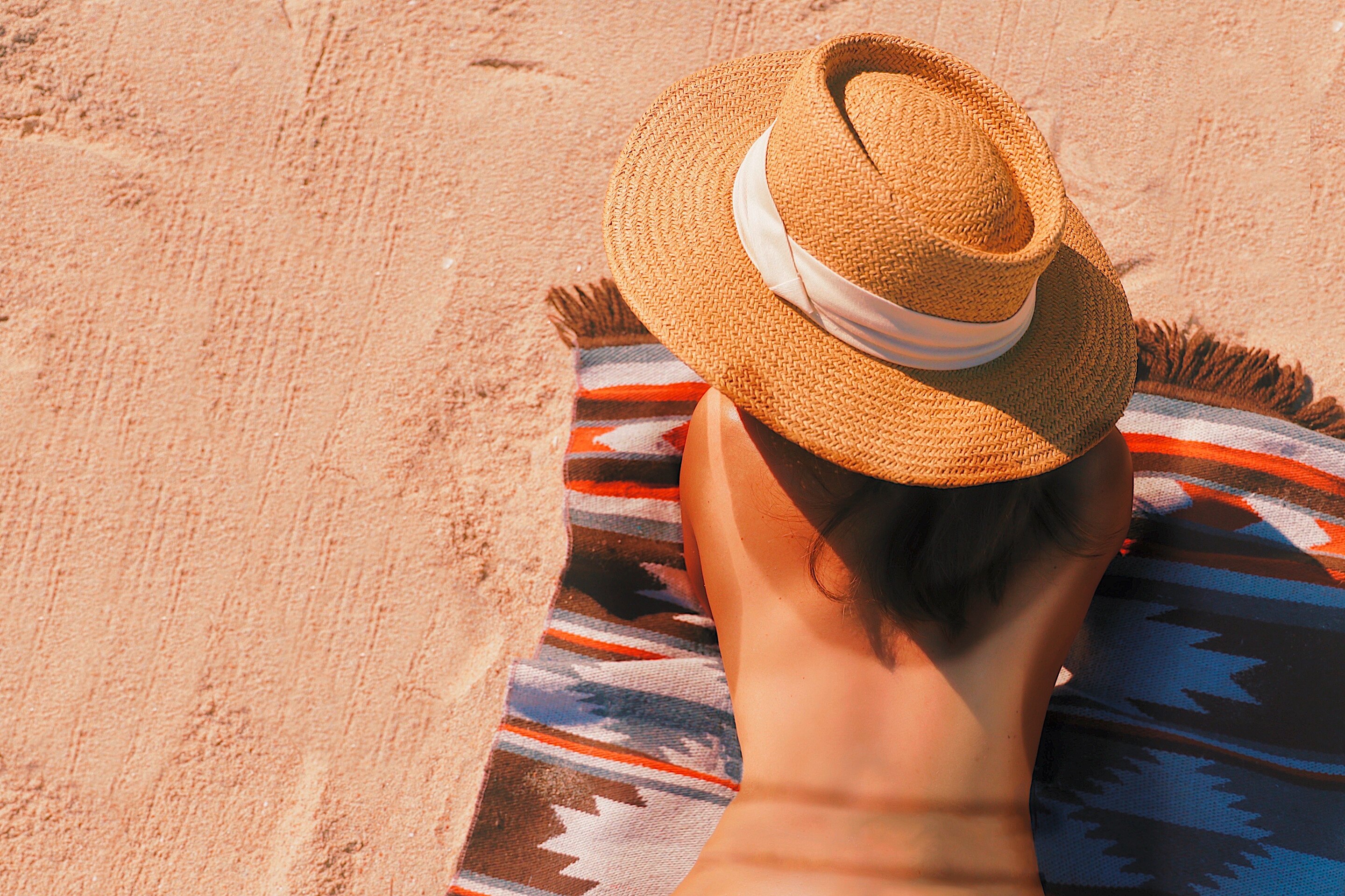 Woman on a beach getting her back tanned.
