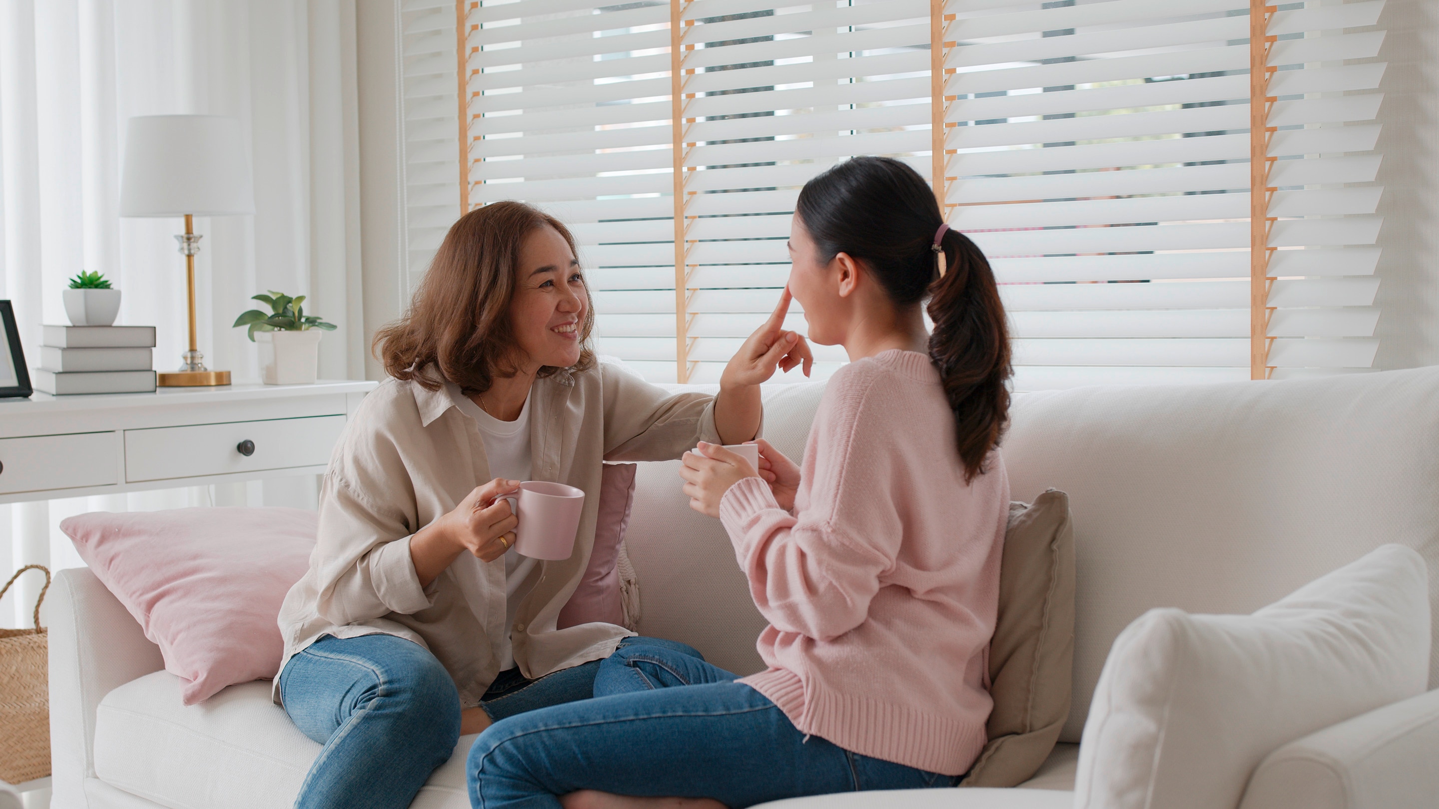 Woman laughing while touching another woman’s nose.