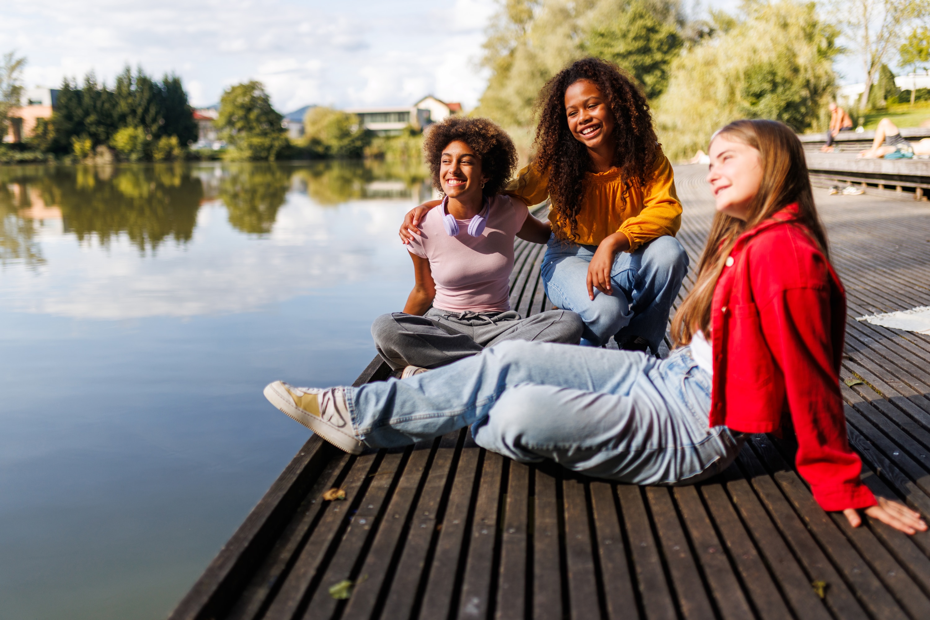 Drei Maedchen sitzen am See
