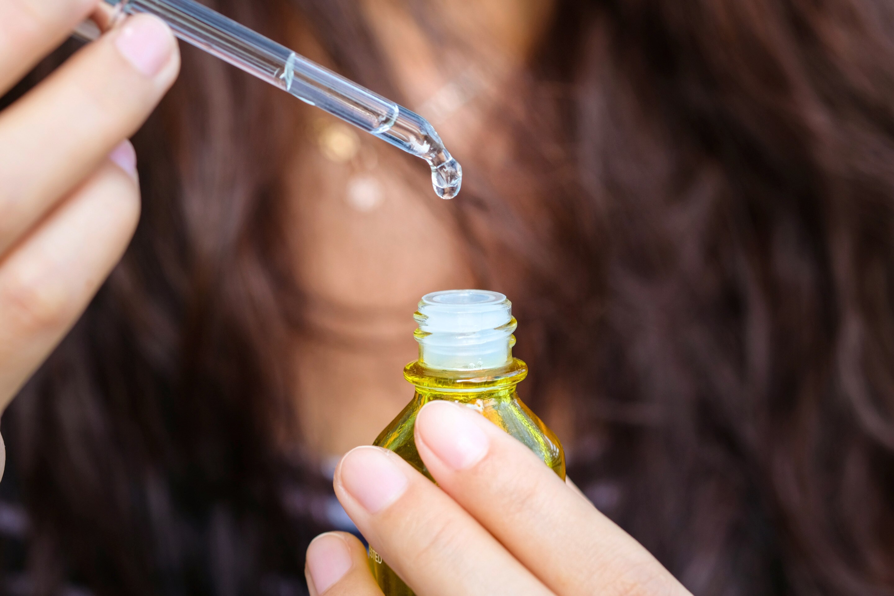 Closeup of woman holding a bottle of face oil.