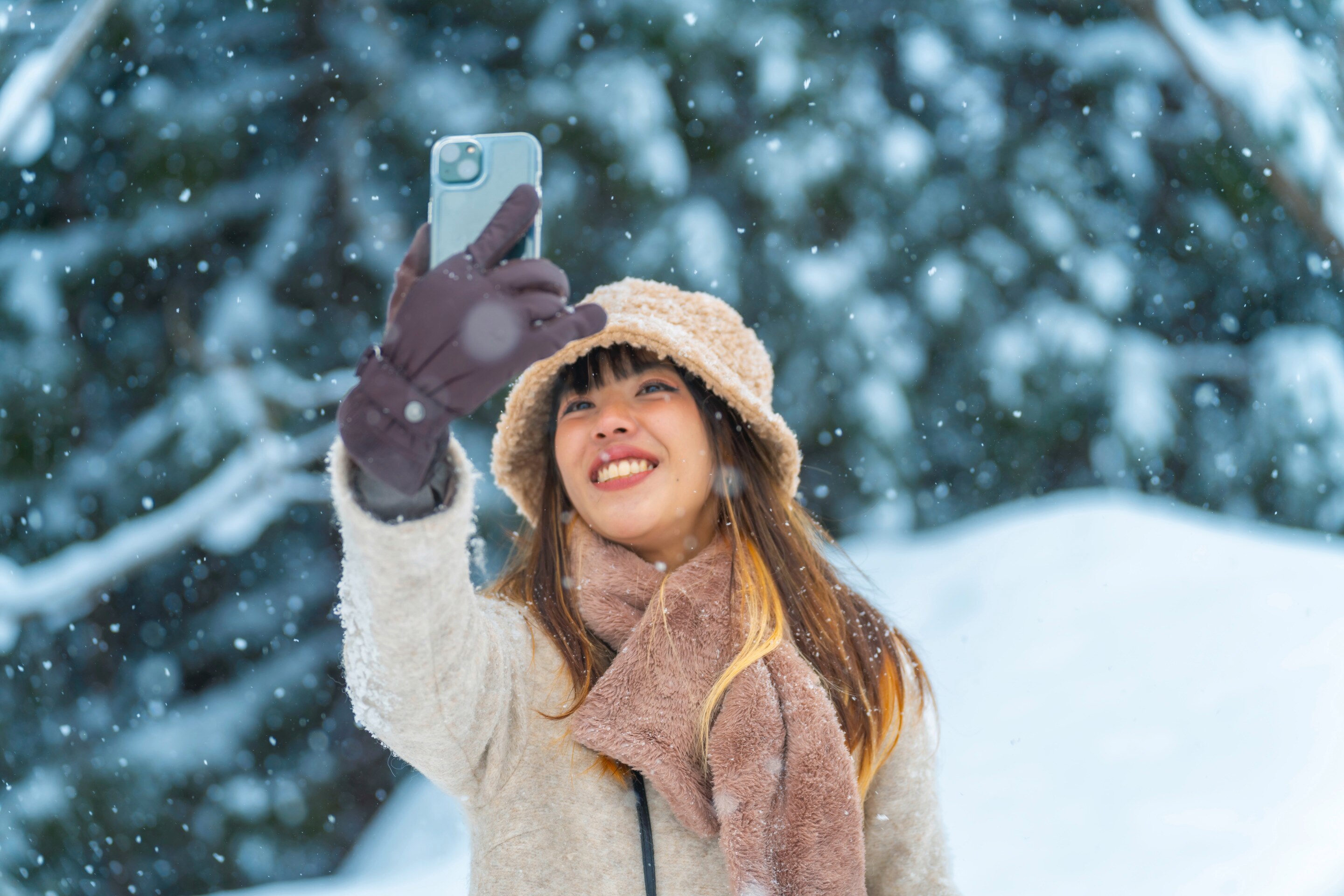 Asian woman taking a selfie on a snowy day. 