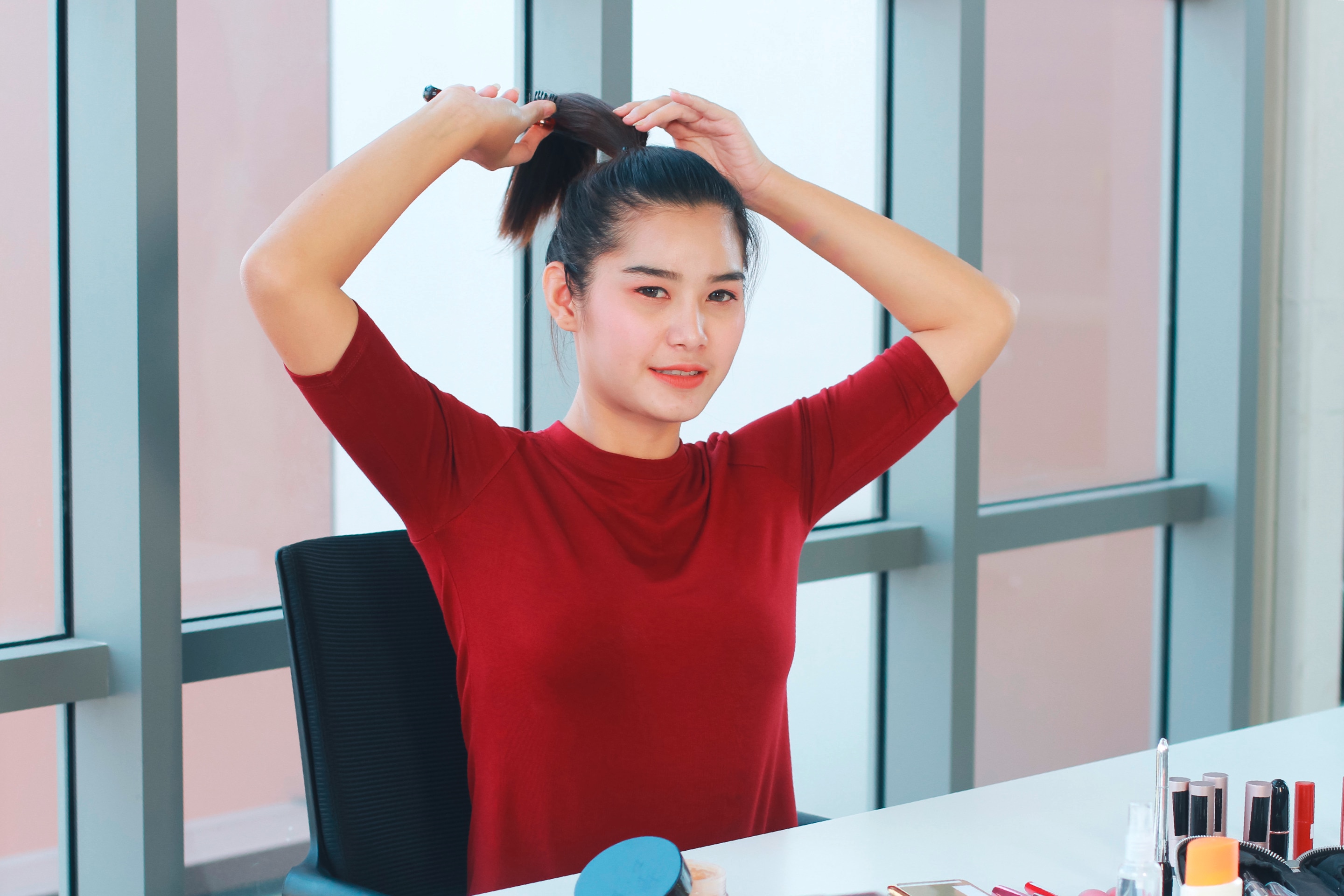 Young woman pulling her hair back to a ponytail.