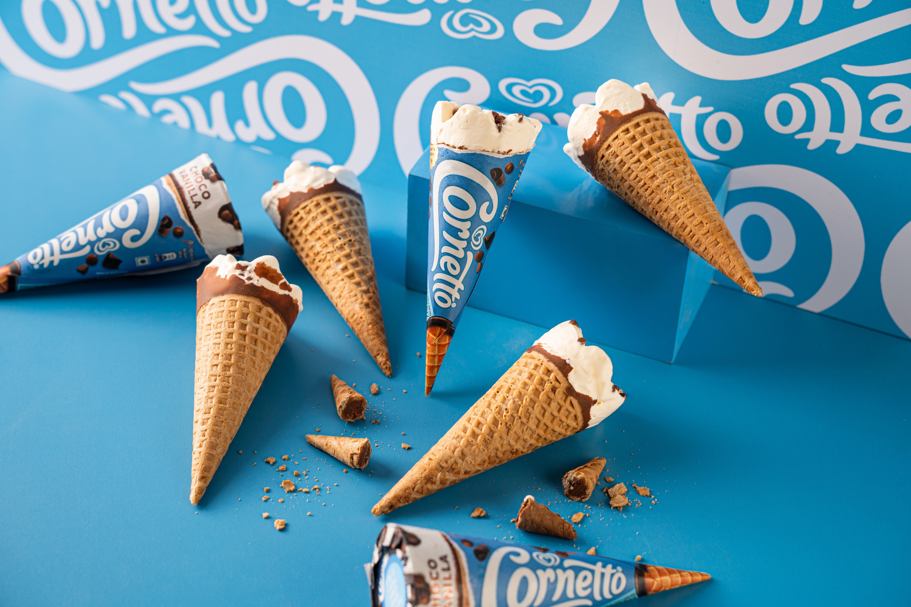 Person at the beach enjoying a bright yellow Magnum popsicle against a clear blue sky
