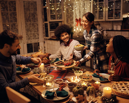 Friends sitting around a dinner table enjoying a meal together for the Holidays
