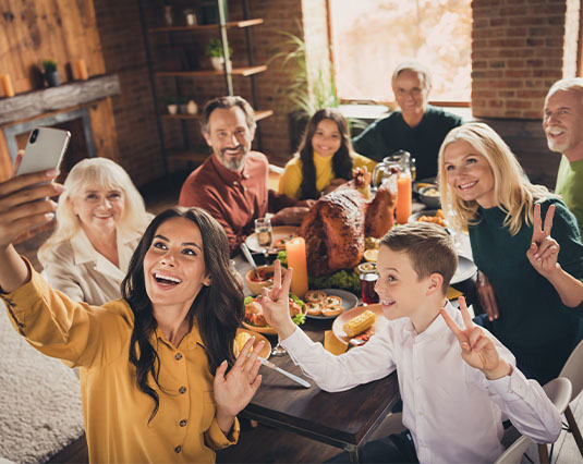 Group of friends and family sitting around a dinner table taking a selfie