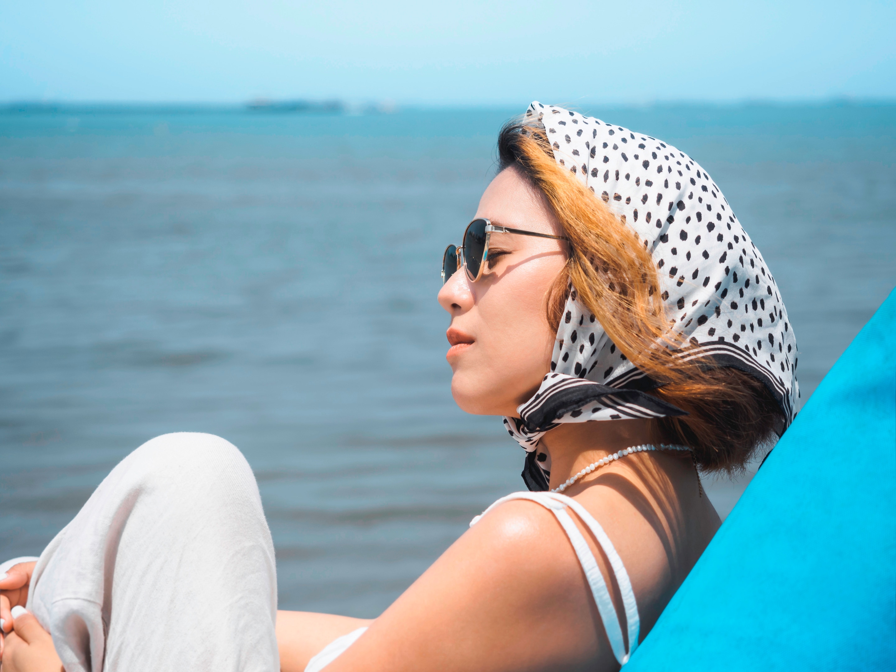 Woman with bleached hair wearing bandana at the beach.