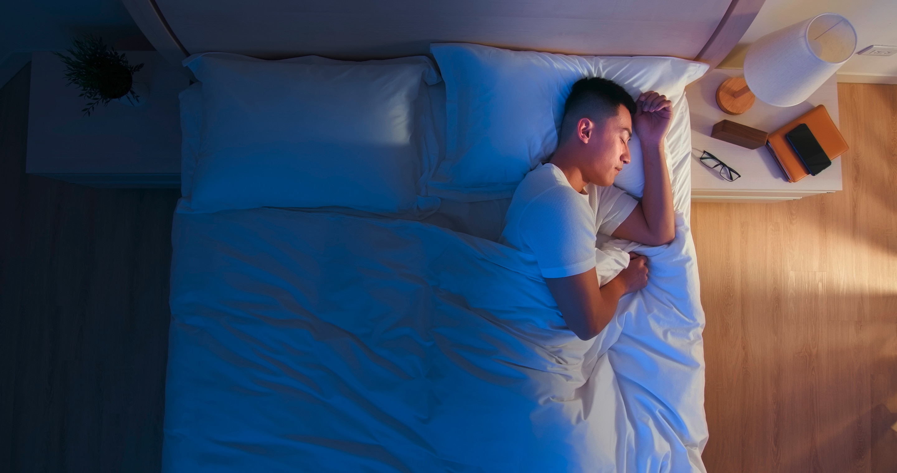 Asian man sleeping in bed.