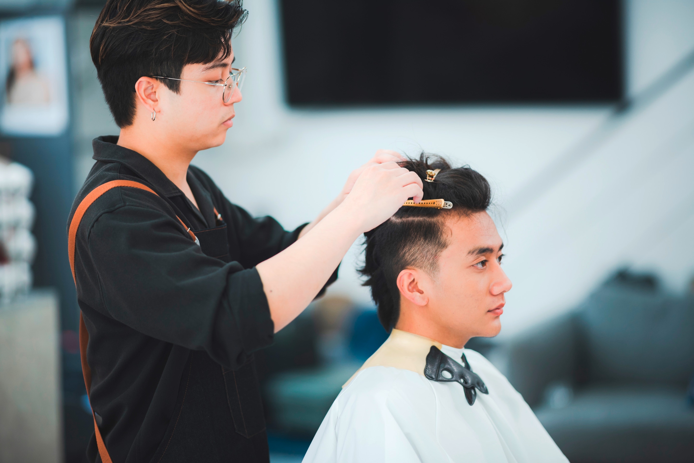 Asian man getting haircut at barbershop.