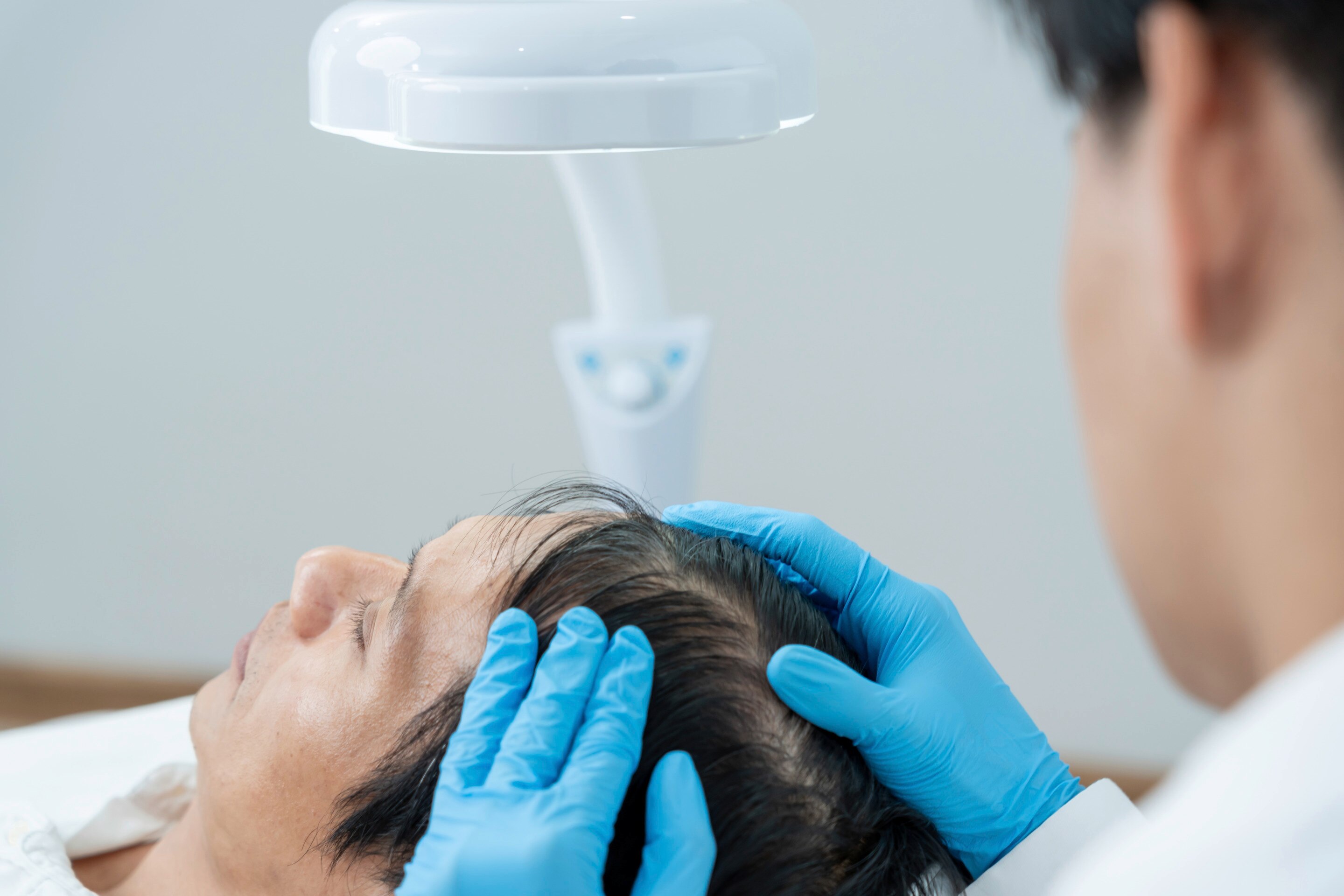 Doctor examines patient’s hair and scalp.