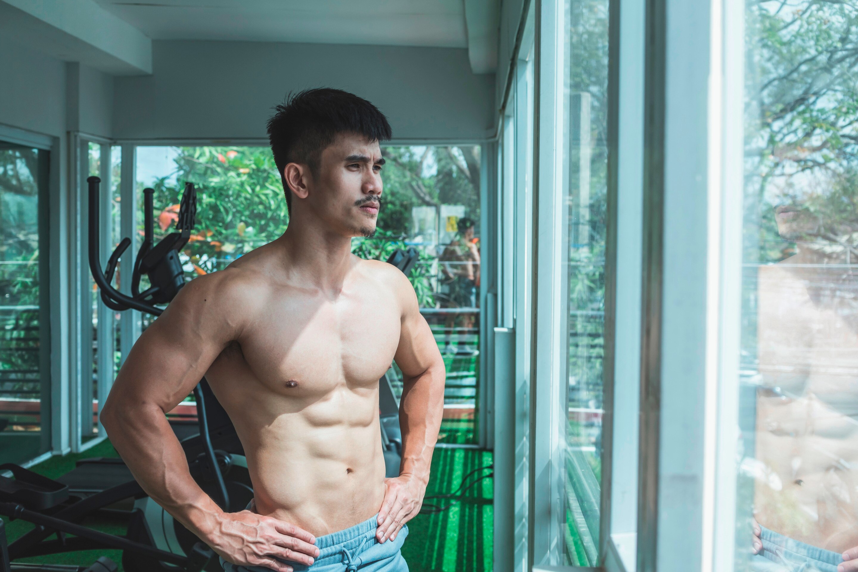 Fit man looks out the window from gym.