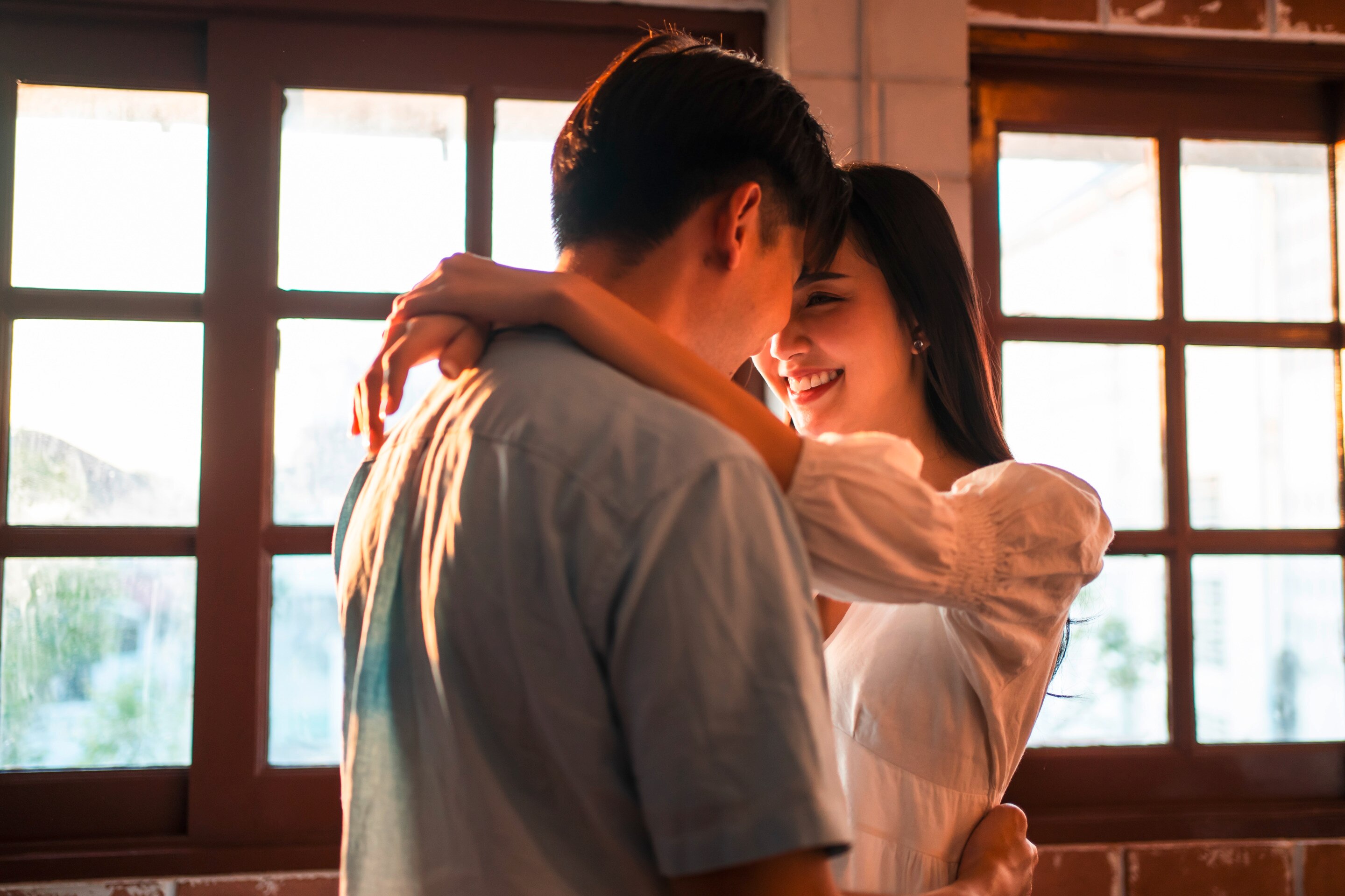 A happy couple with their arms around each other look eye-to-eye lovingly.