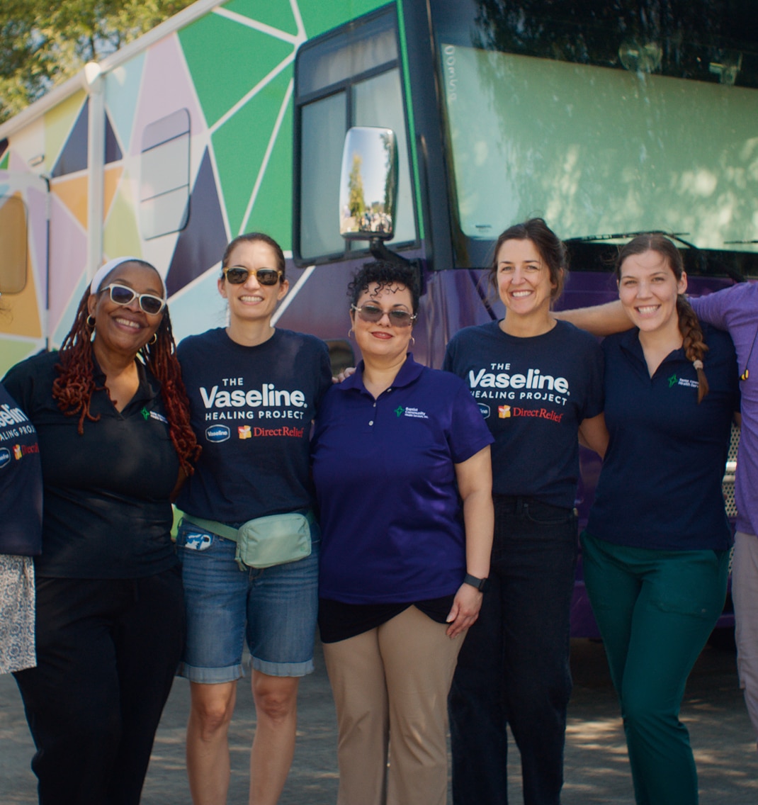 Women standing together outside wearing Vaseline Healing Project shirts