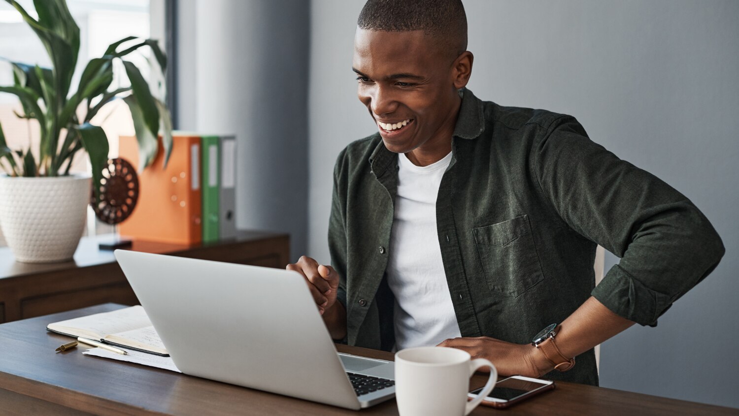 Young African American man sitting at his laptop with hydrated skin after using body wash with glycerin 