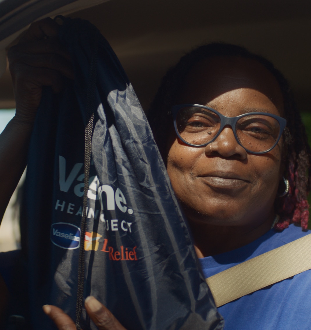 A woman looking at camera and holding a Vaseline Healing Project souvenir