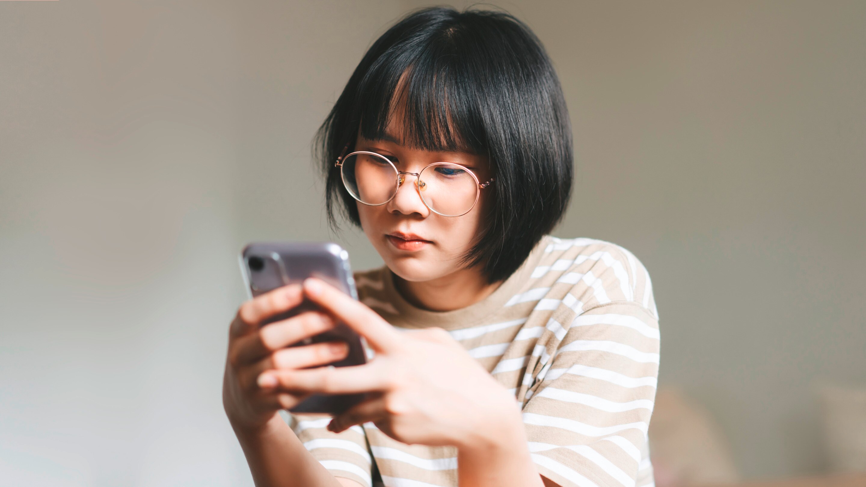 Asian teen looking sad while scrolling.