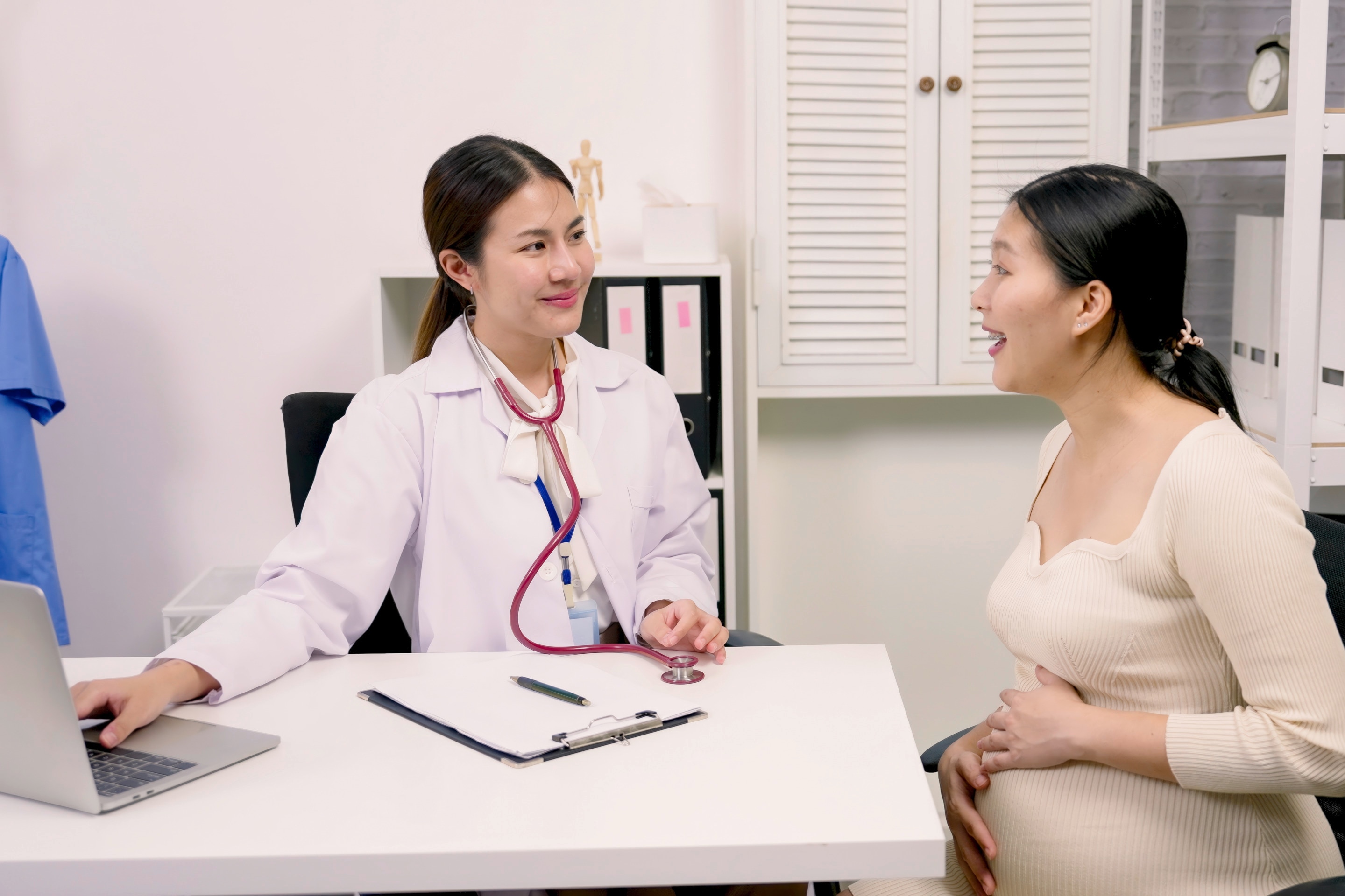 A pregnant Asian woman talking to a female doctor.