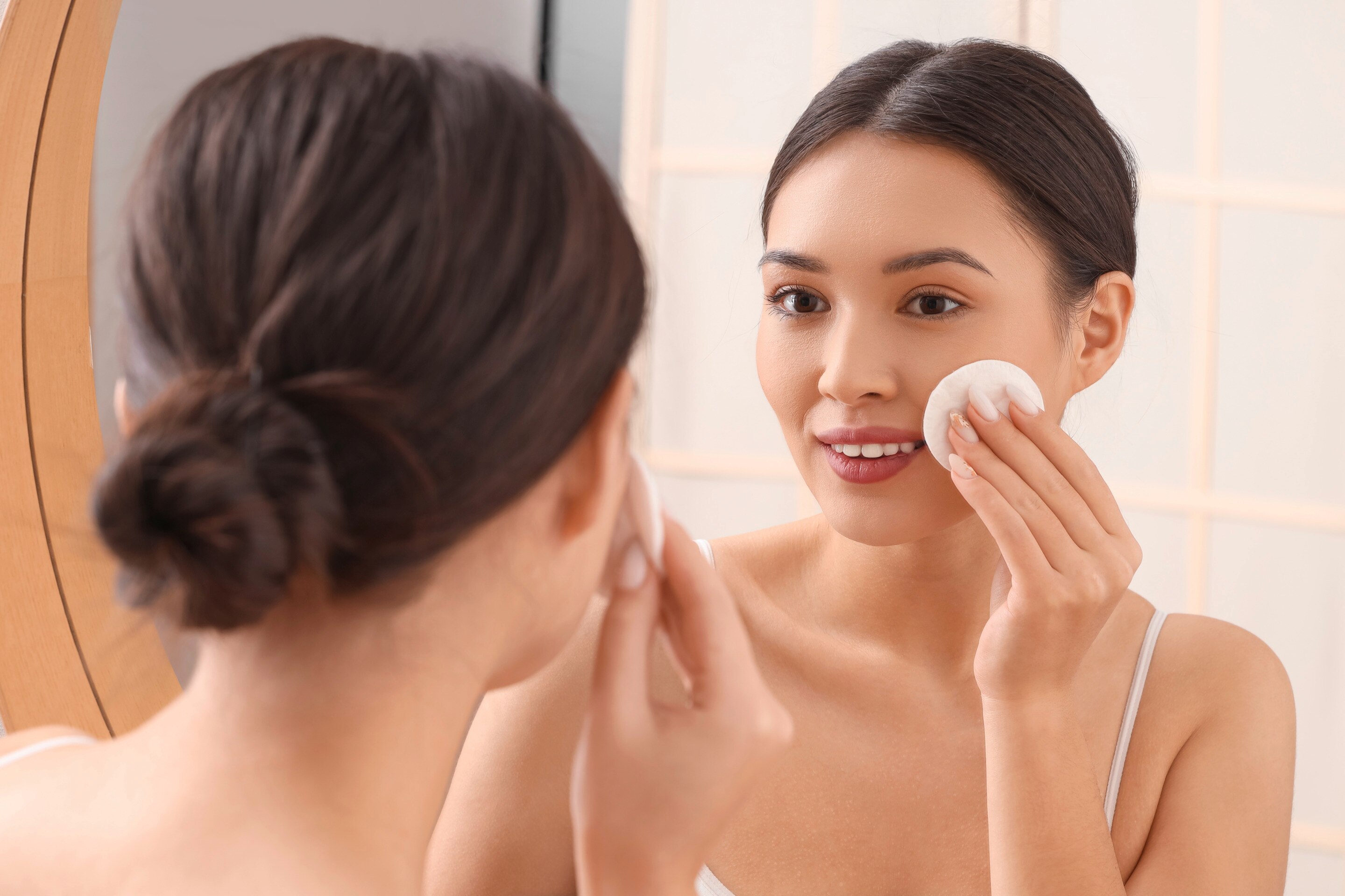 Woman cleansing her face with a cotton pad.