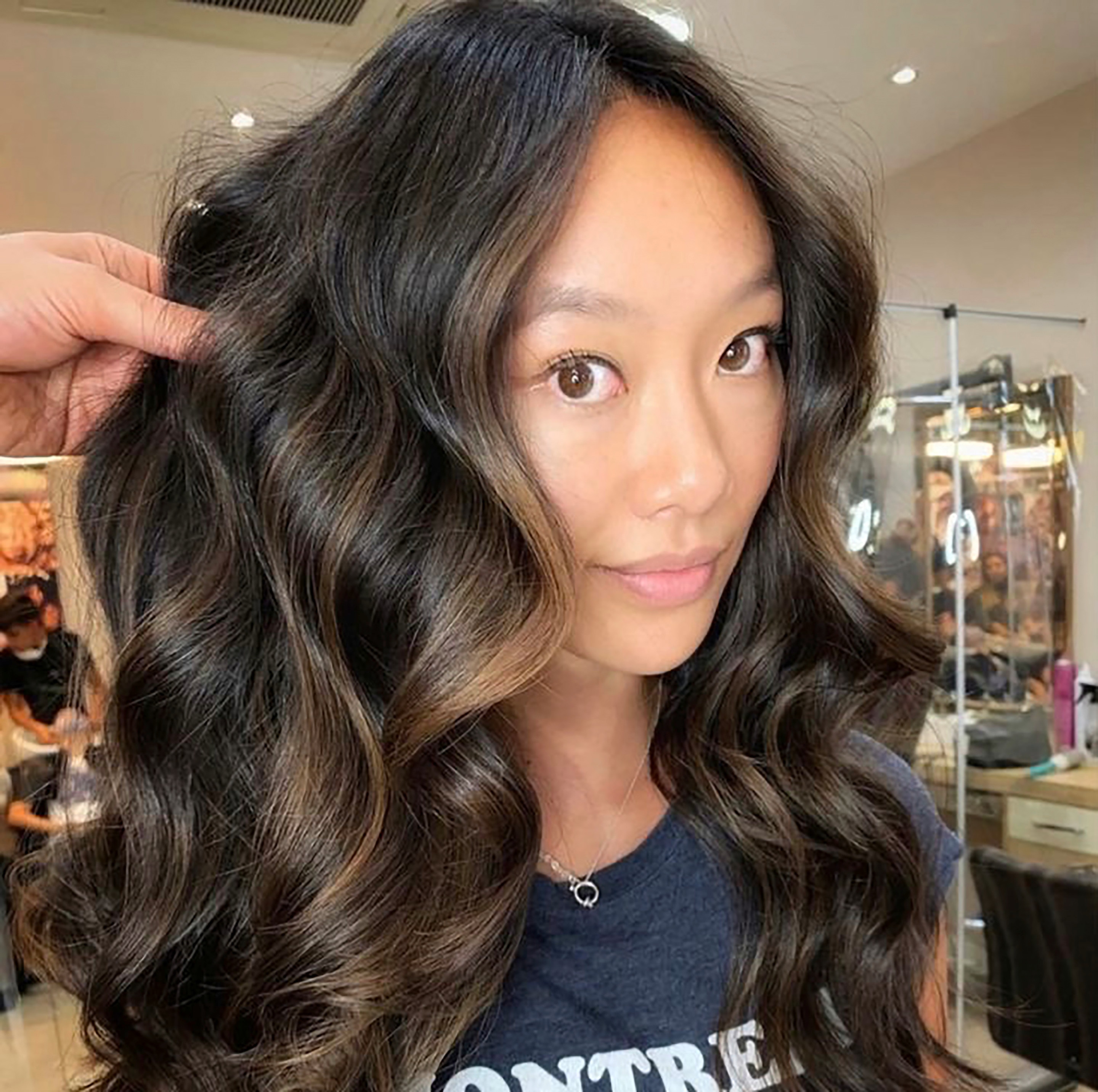 Woman with medium-length wavy hair and face-framing highlights.