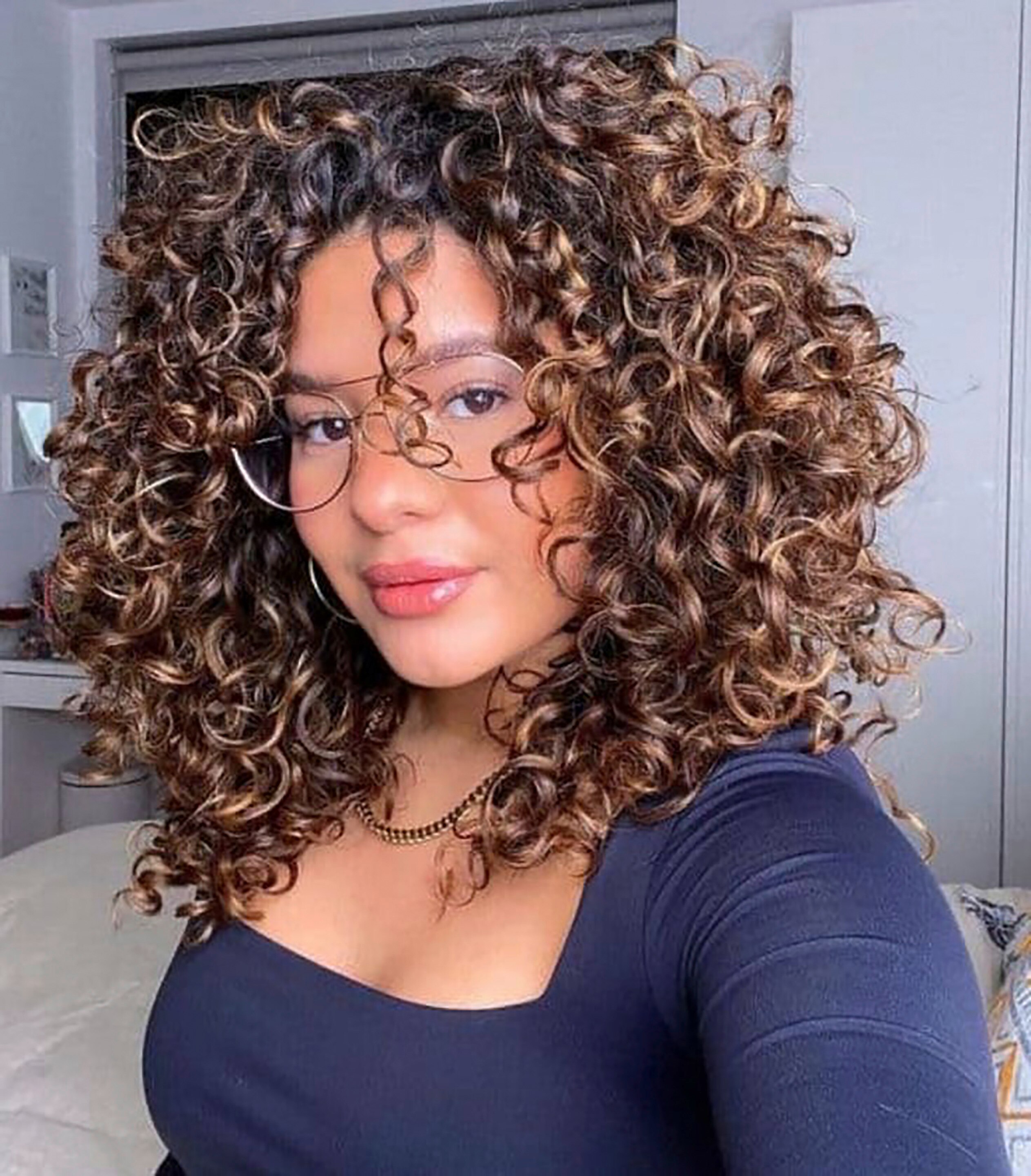 Woman with big, bouncy curly hair and reverse balayage.