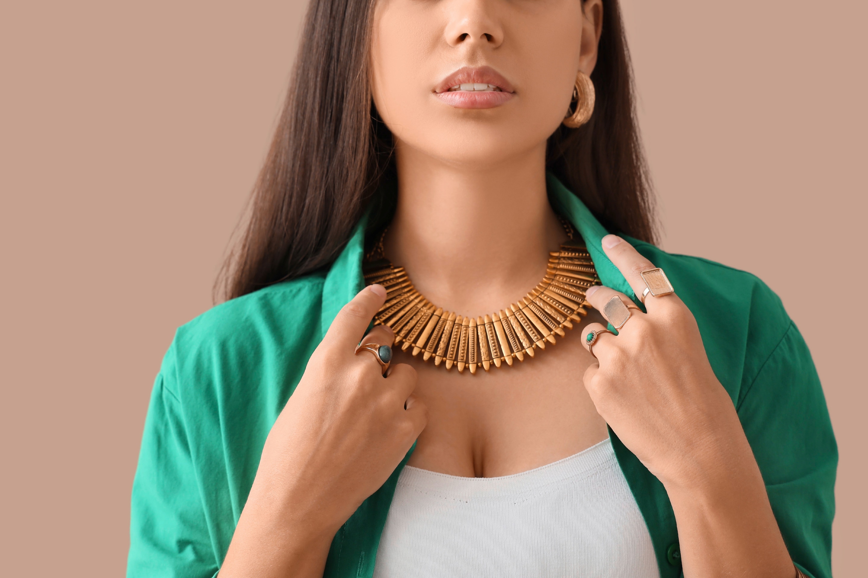 Woman wearing statement necklace, holding her shirt collars.