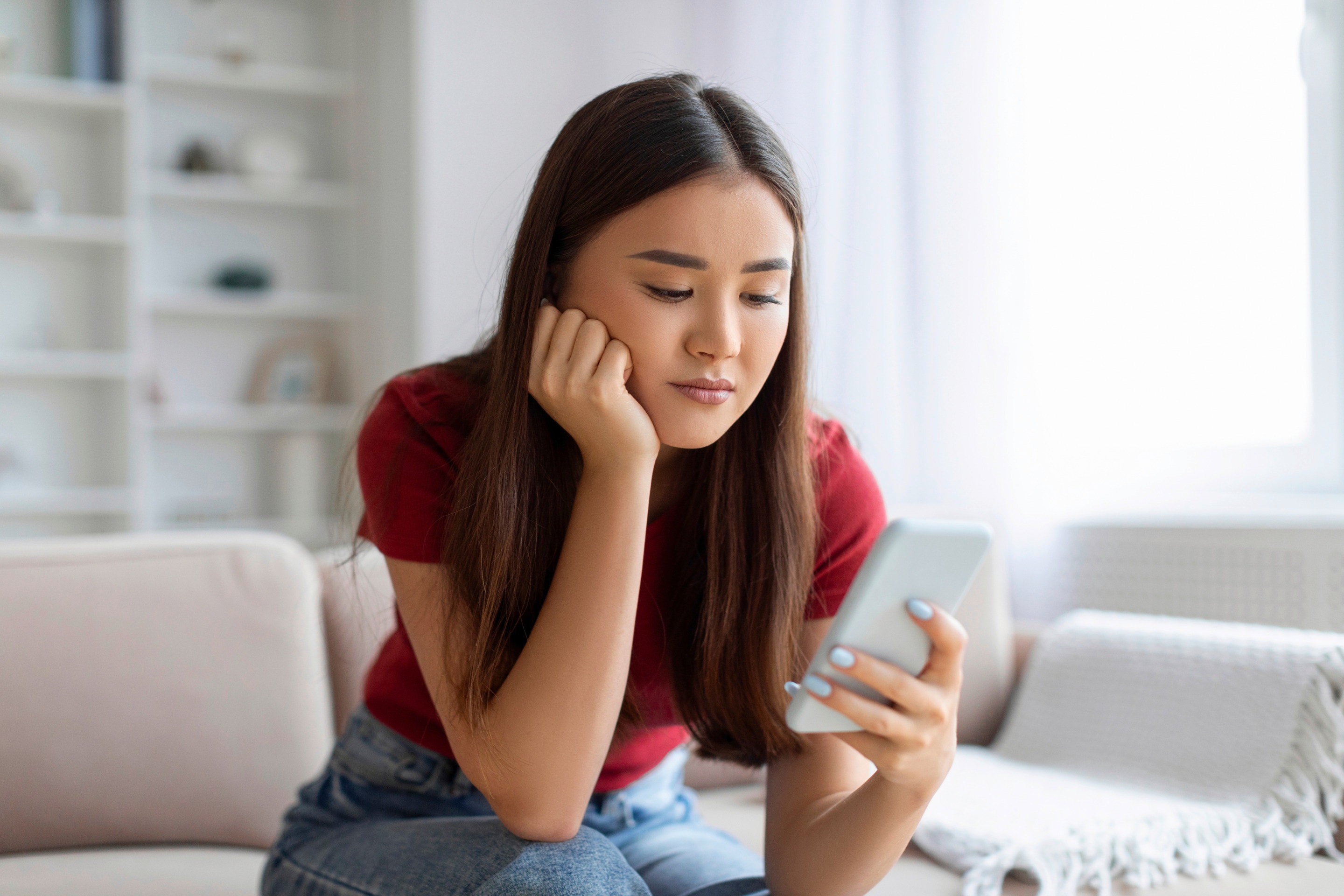 Asian woman slouching while looking at her phone