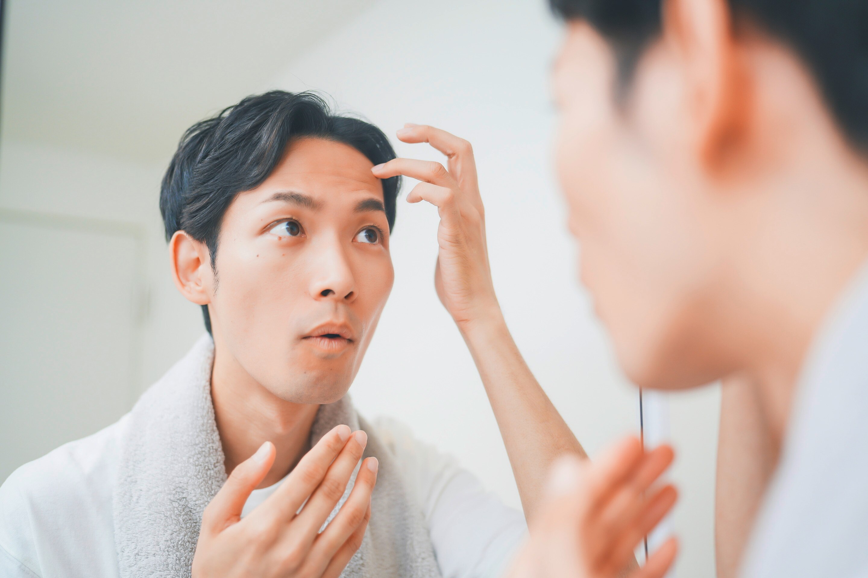 Man applying spot treatment to a pimple on his forehead.