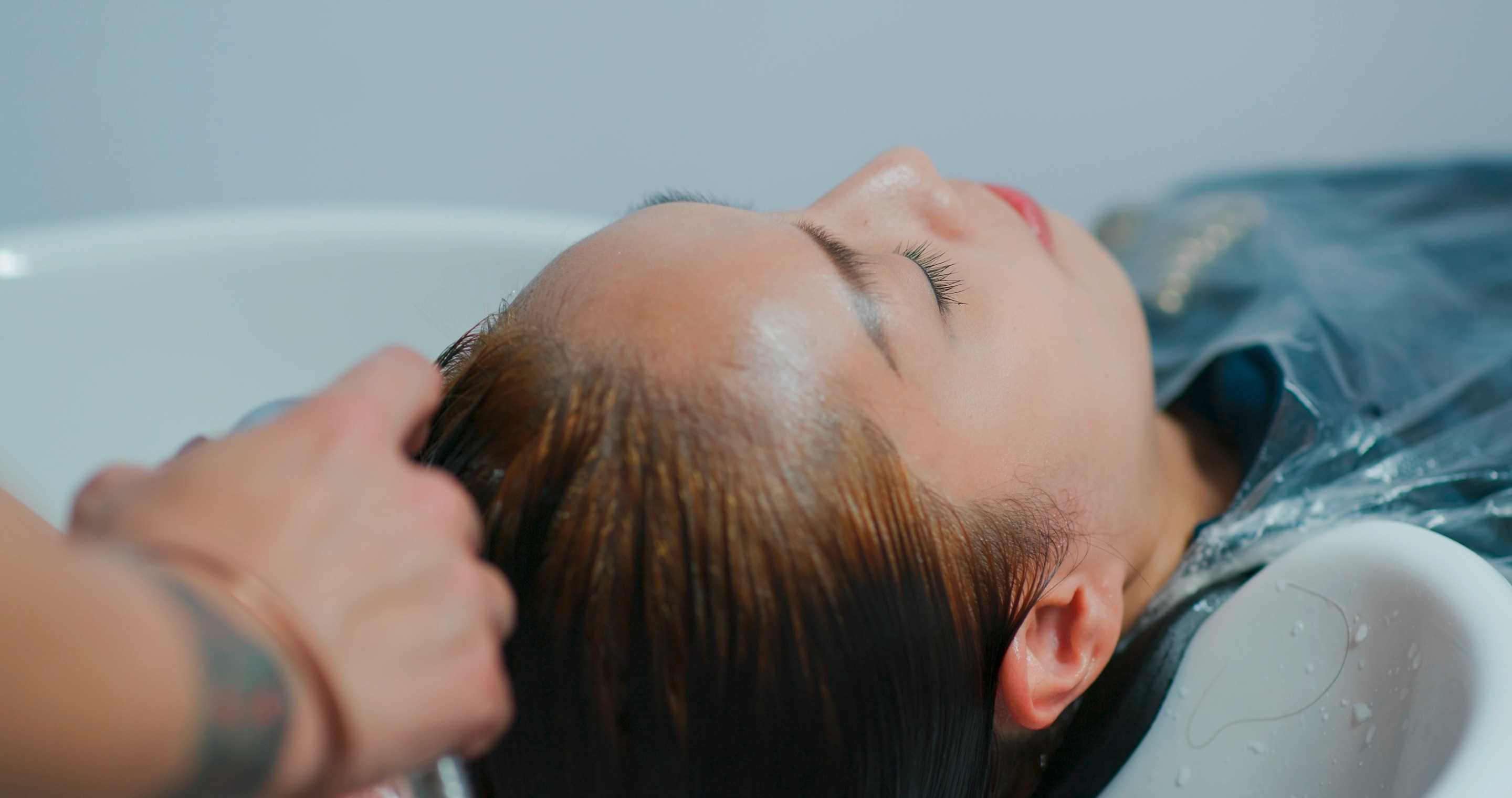 Woman getting her hair rinsed after color treatment.