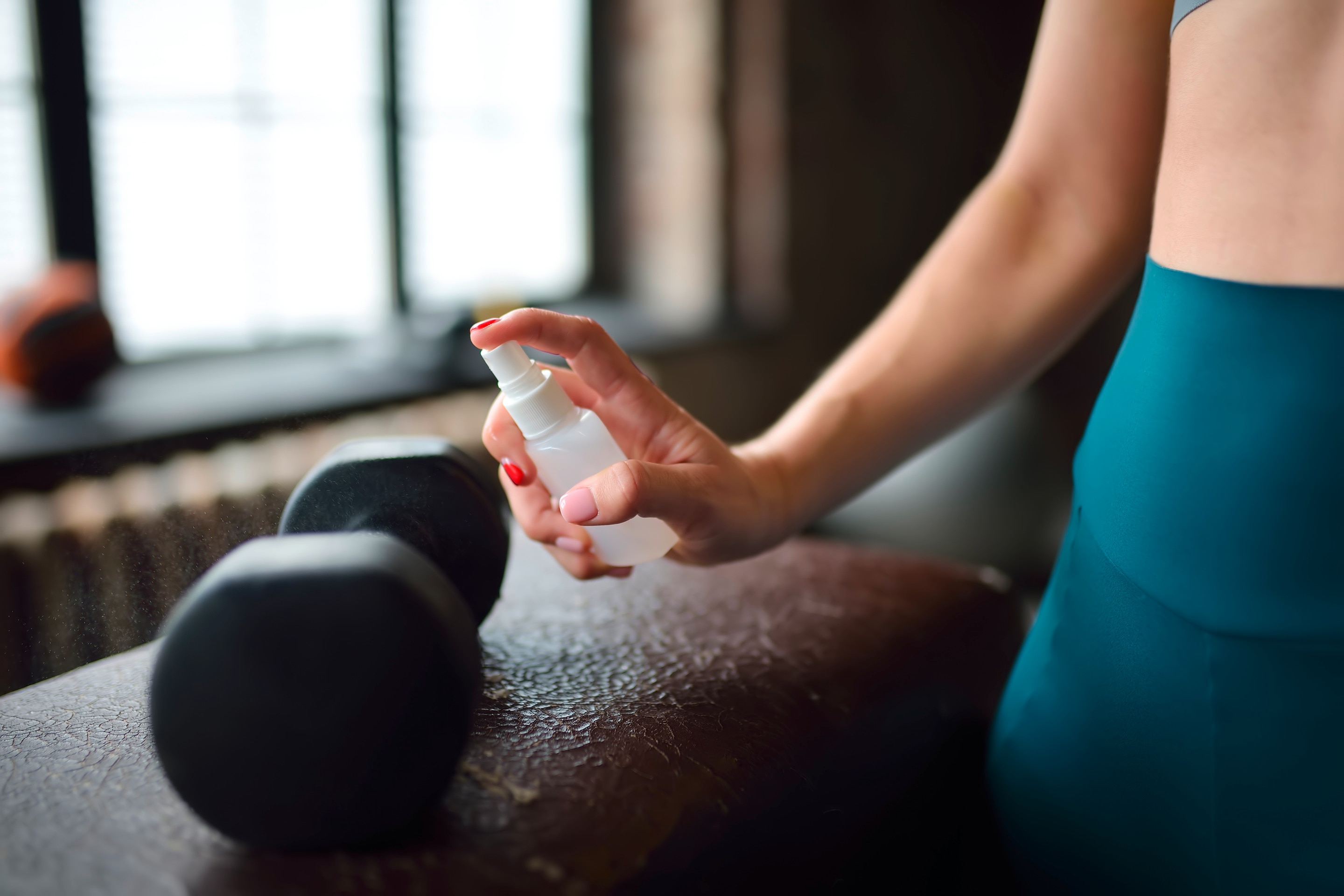 Woman disinfecting gym equipment.