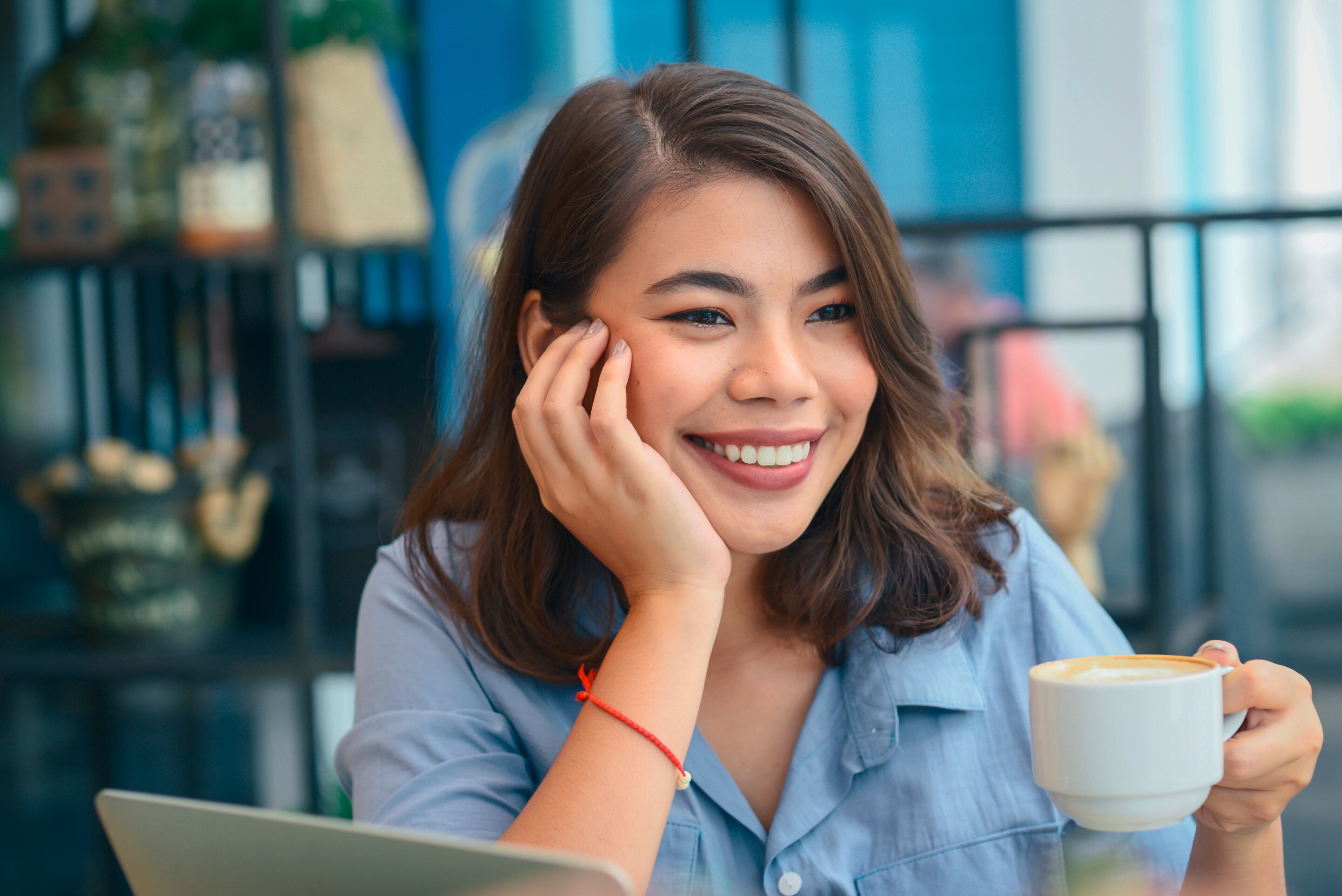 Smiling woman holding a cup of coffee at a café.