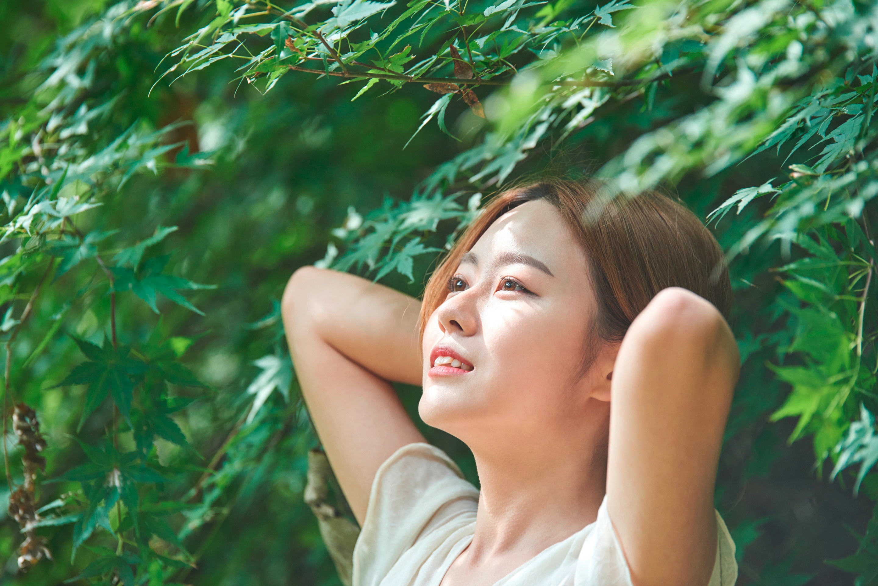 Woman with brown hair standing under a tree.