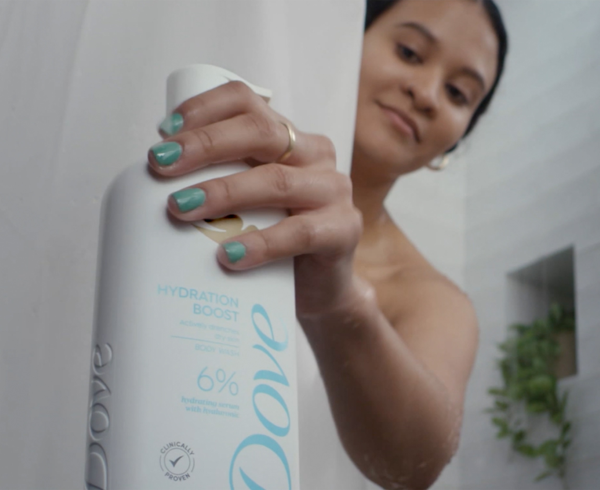 Image of a woman reaching for a bottle of the Dove Hydration Boost Body Wash