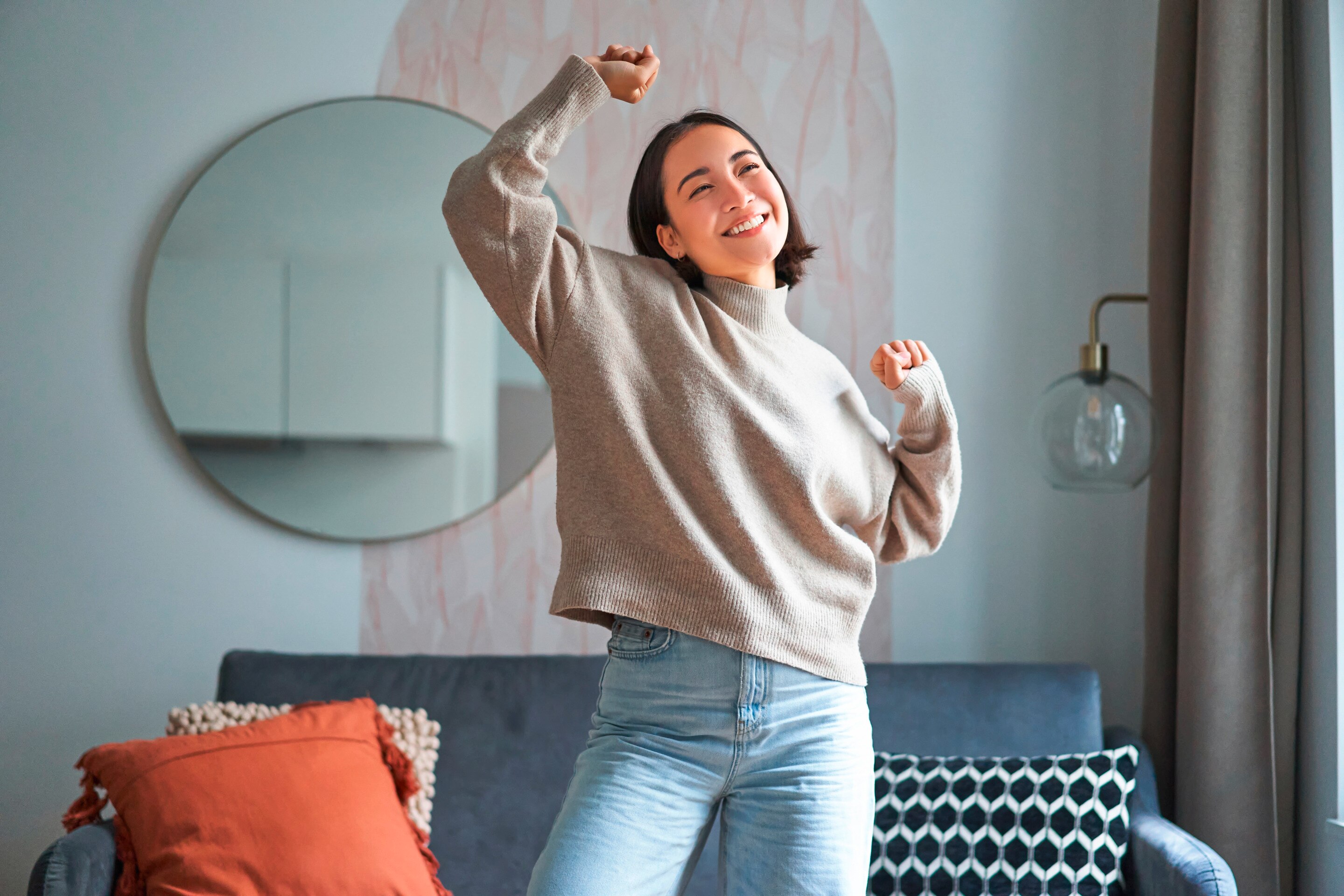 A woman joyfully dances in her living room.